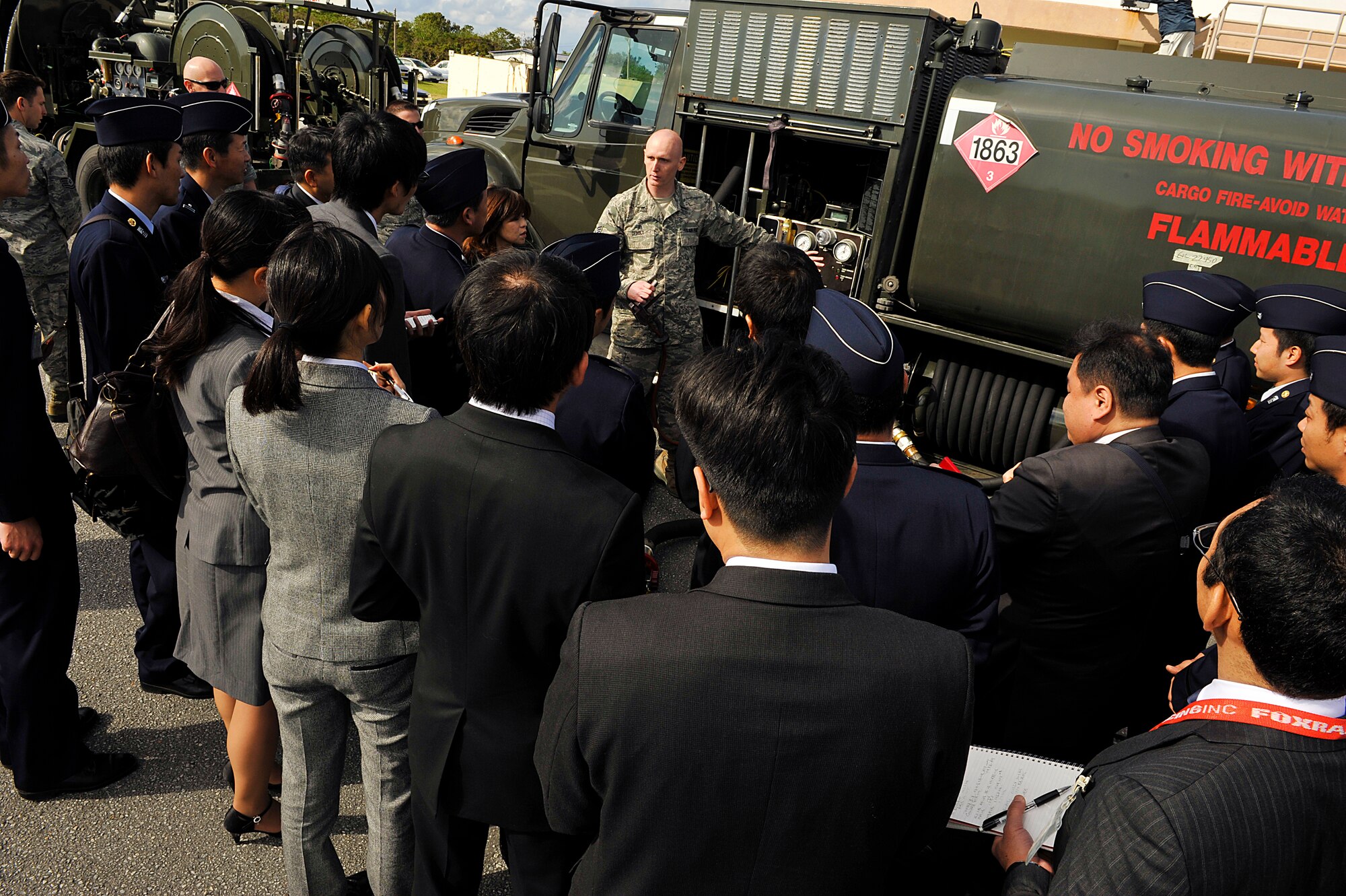 U.S. Air Force Senior Airman Michael Debolt, 18th Logistics Readiness Squadron fuels distribution operator, explains the features of an R-11 fuel truck to Japan Air Self Defense Force members during their visit to Kadena Air Base, Okinawa, Japan, Feb. 10, 2015. A total of 26 JASDF members toured Kadena's supply facilities to learn how the U.S. Air Force side of the supply operates. (U.S. Air Force photo by Naoto Anazawa)