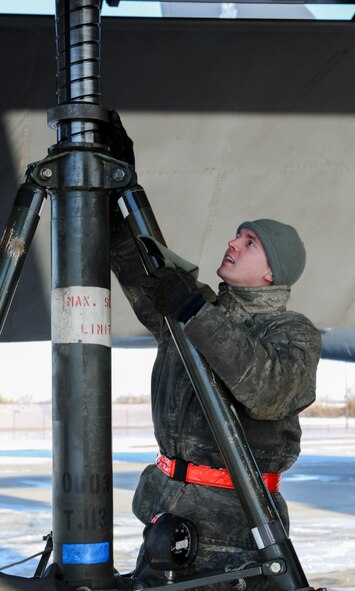 Airman 1st Class Zachary Jensen, 5th Maintenance Squadron repair and reclamation journeyman, adjusts a hydraulic jack under the wing of a B-52H Stratofortress on Minot Air Force Base, N.D., Feb. 4, 2015. Jensen and his team use the jack during a tip gear operation check. Tip gear protects the wings of the aircraft from damage as they flex during landing. (U.S. Air Force photo/Senior Airman Stephanie Morris)