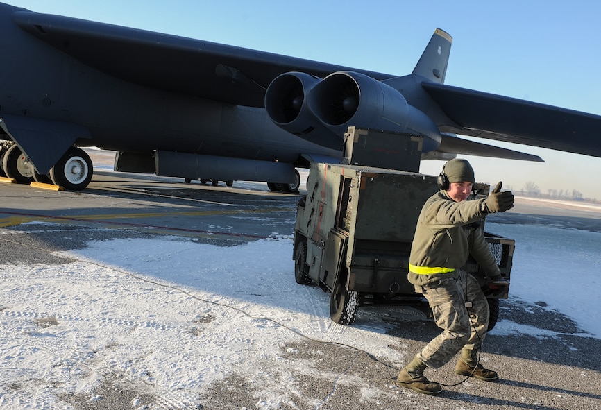 Senior Airman Sergei Amos, 5th Aircraft Maintenance Squadron crew chief, motions for a ground heater to be picked up on Minot Air Force Base, N.D., Feb. 4, 2015. The heater was used to warm the engines before they were turned on. (U.S. Air Force photo/Senior Airman Stephanie Morris)