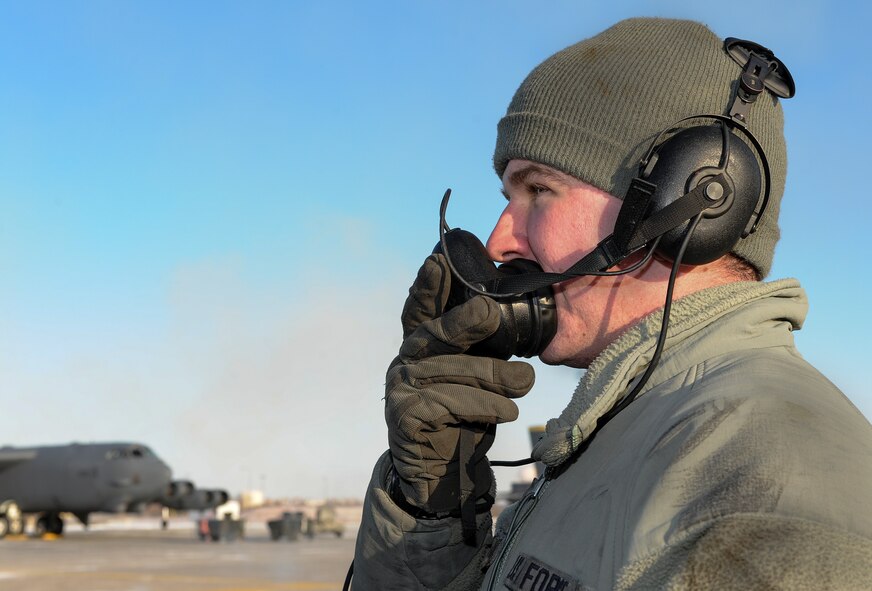 Senior Airman Sergei Amos, 5th Aircraft Maintenance Squadron crew chief, speaks to the aircrew of a B-52H Stratofortress through a mouthpiece on Minot Air Force Base, N.D., Feb. 4, 2015. Amos relays preflight check information to the crew and addresses any discrepancies they notice from the cockpit. (U.S. Air Force photo/Senior Airman Stephanie Morris)