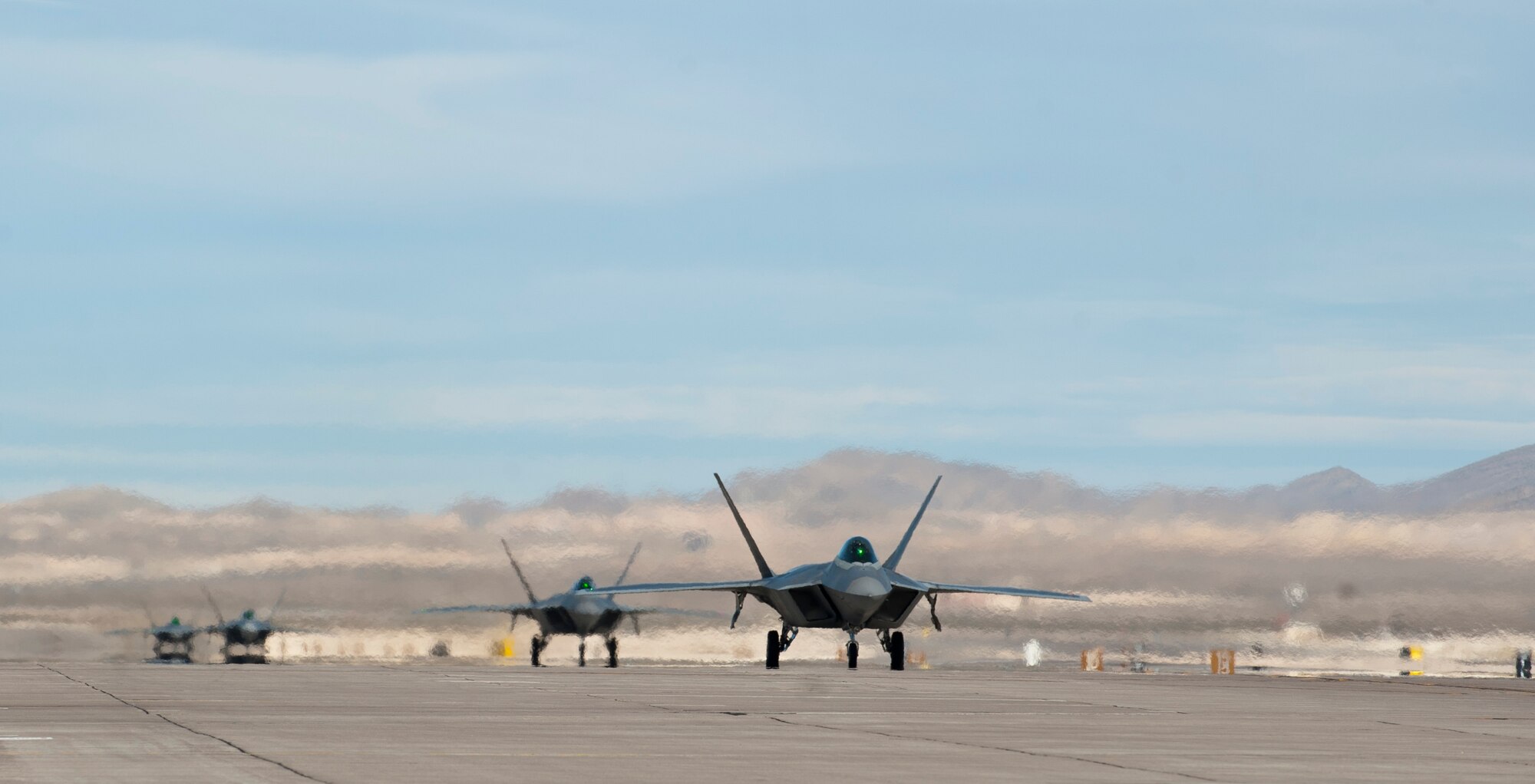 Four F-22 Raptors assigned to the 94th Fighter Squadron, Joint Base Langley-Eustis, Va., taxi to the runway during Red Flag 15-1 at Nellis Air Force Base, Nev., Feb. 6, 2015. Red Flag provides a series of intense air-to-air combat scenarios for aircrew and ground personnel which will increase their combat readiness and effectiveness for future real world missions. (U.S. Air Force photo by Senior Airman Thomas Spangler)