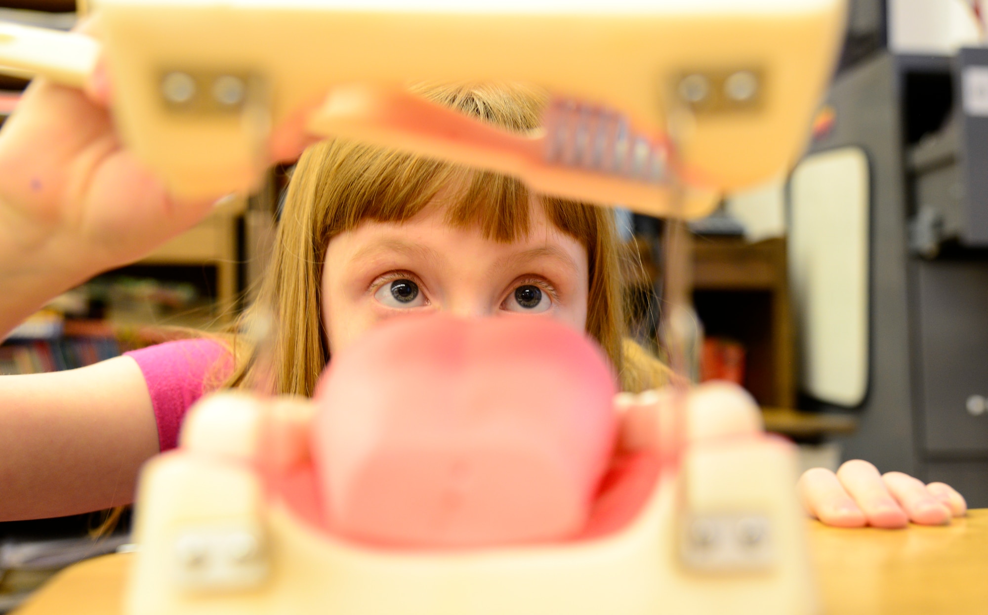 Hailey Kossow, a dental health month participant, demonstrates proper brushing techniques for hard to reach teeth during a National Children’s Dental Health month demonstration at Anderson Elementary, Eielson Air Force Base, Alaska, Feb. 10, 2015. Icemen from the dental office explained the importance of staying away from sugary foods, eating a healthy diet, how toothpaste is a vitamin for teeth and gave brushing and flossing techniques. (U.S. Air Force photo by Senior Airman Racheal E. Watson/Released)