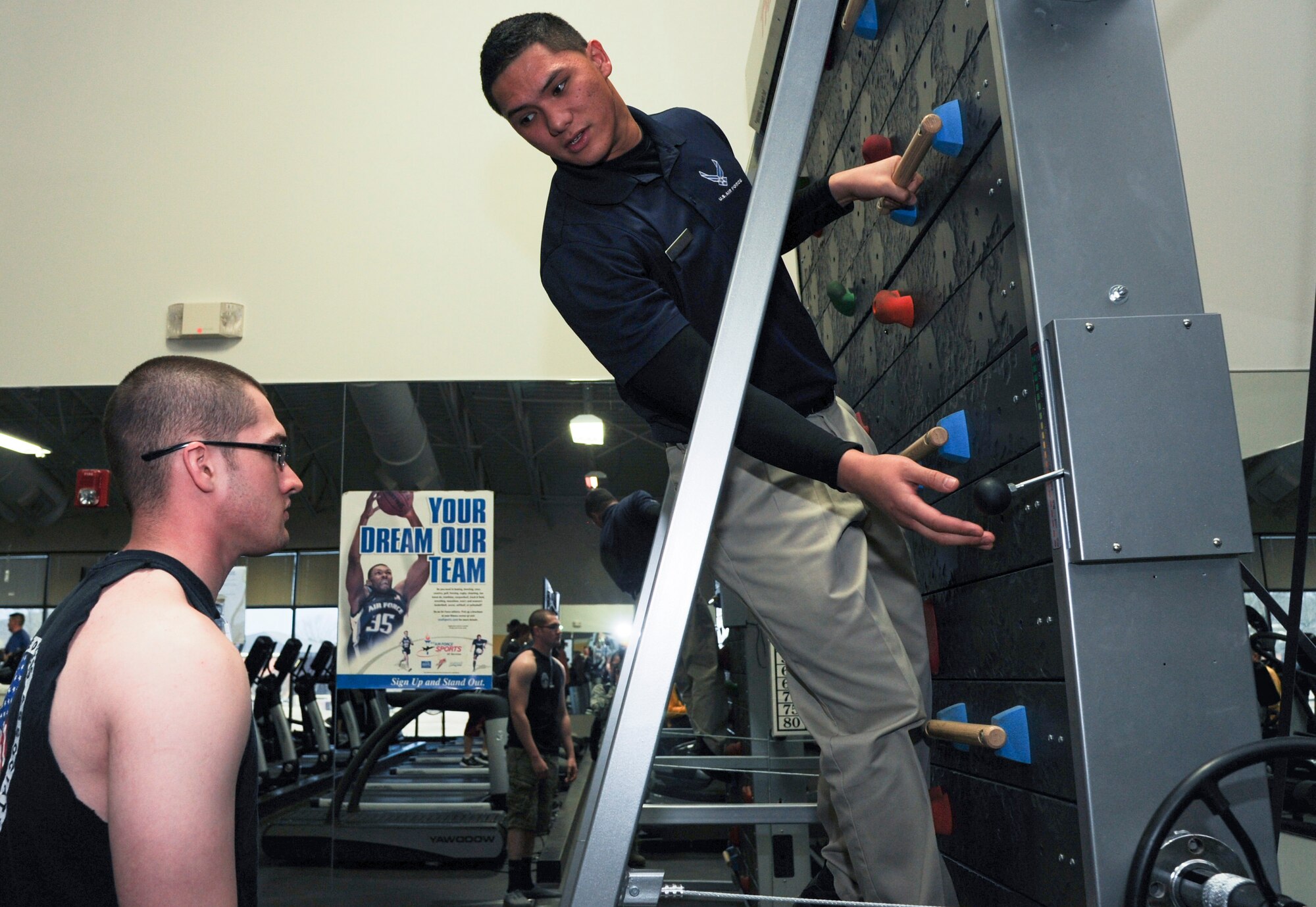 Senior Airman Frederick Burgos, a 19th Force Support Squadron fitness specialist, instructs a gym-goer on how to use the treadwall Feb. 9, 2015, at Little Rock Air Force Base, Ark. In addition to the treadwall, Burgos oversaw the purchase, assembly and customer familiarization of 52 new cardio equipment pieces. (U.S. Air Force photo by Airman 1st Class Mercedes Muro)
