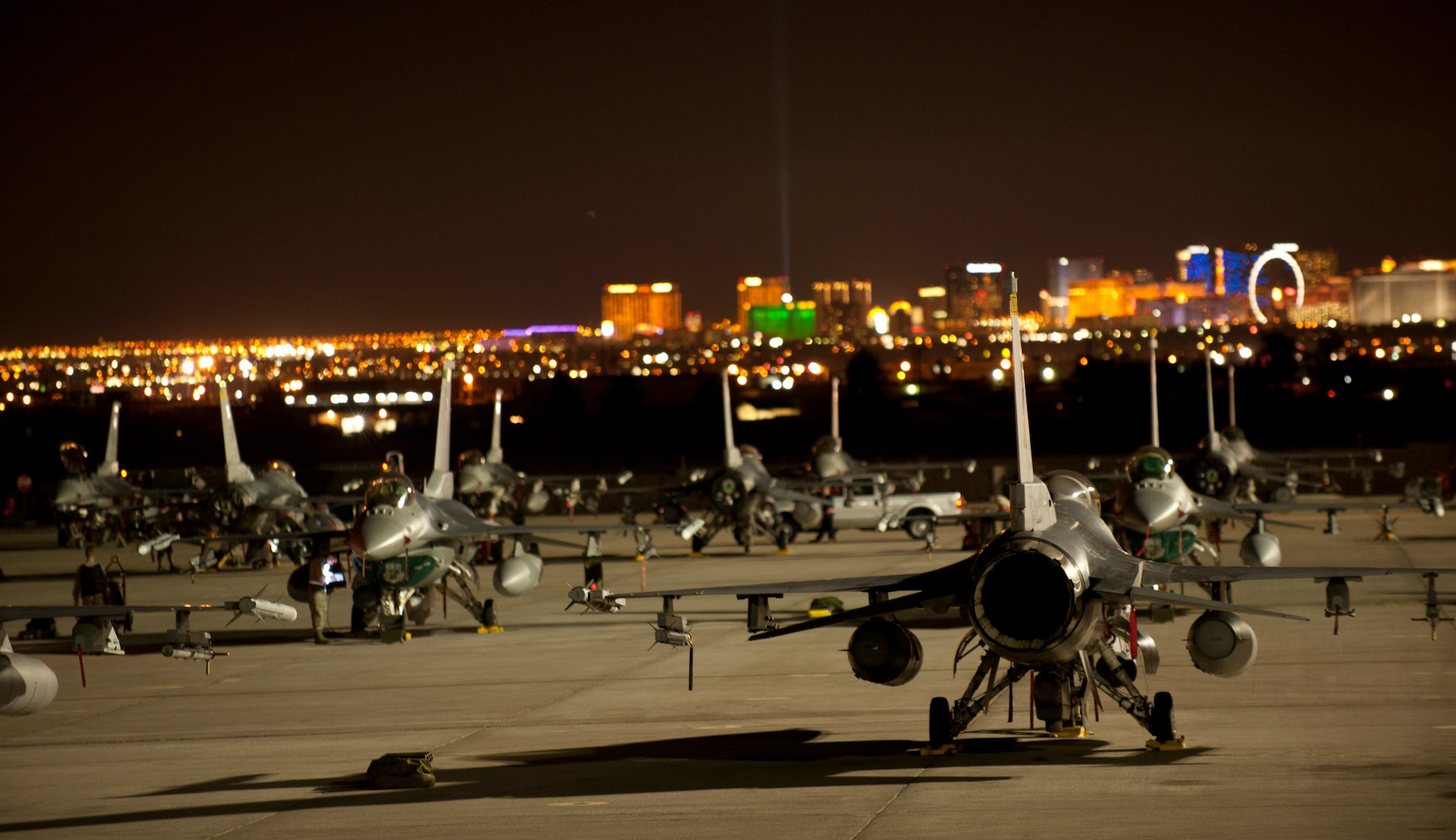 F-16 Fighting Flacons assigned to the 134th Fighter Squadron, Burlington Air National Guard Base, Vt., stand ready on the flightline overlooking the Las Vegas strip prior to playing part in a Red Flag 15-1 night training sortie at Nellis Air Force Base, Nev., Feb. 4, 2015. During Red Flag exercises, the Nellis flightline can be home to more than 150 U.S. Air Force, joint and coalition aircraft. (U.S. Air Force photo by Airman 1st Class Joshua Kleinholz)