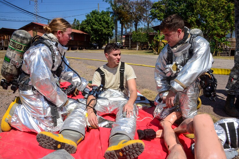 U.S. Air Force Airman 1st Classes Adrianna Hopkins and Gregory Pease, 612th Air Base Squadron firefighters, help provide simulated medical attention to U.S. Air Force Senior Airman Collin Lorash, 612th Air Base Squadron firefighter, during a hazardous material exercise on Soto Cano Air Base, Honduras, Feb. 10, 2015. The training exercise was held to guarantee members assigned to the 612th ABS Fire Department are compliant with the Department of Defense’s requirement that all Air Force firefighters are certified to the hazmat technical level. (U.S. Air Force photo/Tech. Sgt. Heather Redman)
