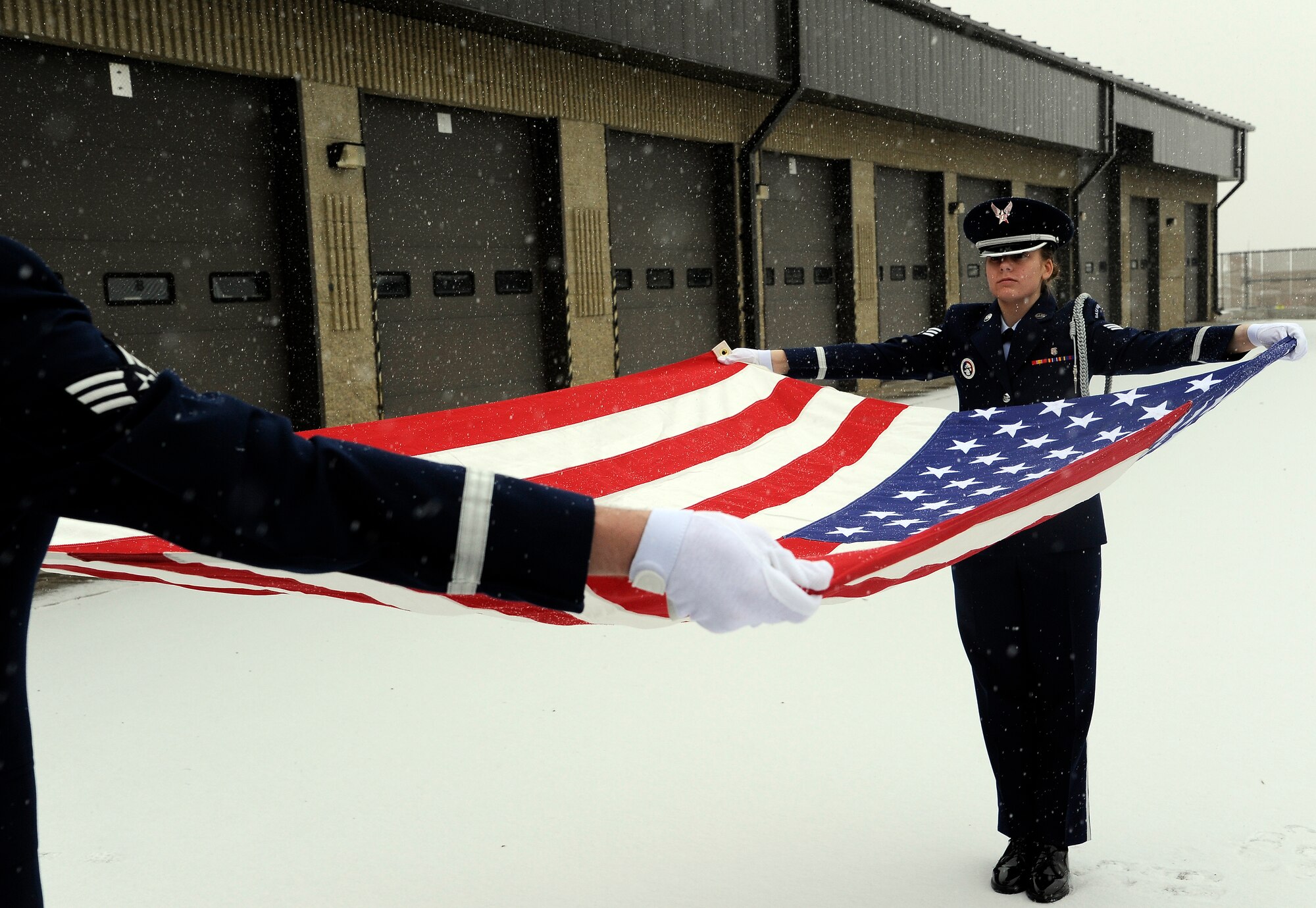 Senior Airmen Whitney Eisinger and Donald Myers, Malmstrom Air Force Base Honor Guard members, practice unfolding the flag into the table-top position during their honor guard duty week. The two-person flag fold is the sequence normally performed by the Malmstrom Honor Guard. There are two different flag folding sequences utilized by the Air Force base honor guard, the two-person and the six person flag fold. (U.S. Air Force photo/Staff Sgt. Delia Marchick)