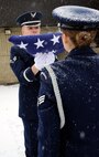 Senior Airman Donald Myers presents the folded flag to Senior Airman Whitney Eisinger, both Malmstrom Air Force Base Honor Guard members, as they practice the two-person flag folding during training days of their duty week. (U.S. Air Force photo/Staff Sgt. Delia Marchick)