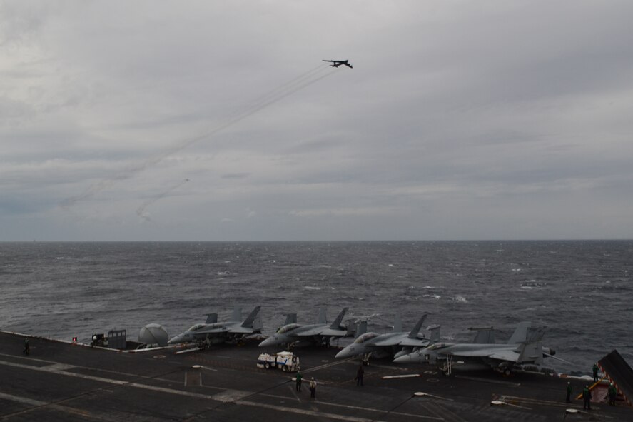 A B-52H Stratofortress from Minot Air Force Base, N.D. flies over aircraft carrier USS Theodore Roosevelt during a Composite Training Unit Exercise, Jan. 8, 2014. The Composite Training Unit Exercise tests the Theodore Roosevelt Carrier Strike Group's ability to effectively react to real-world scenarios and perform as an integrated unit. (Courtesy photo)