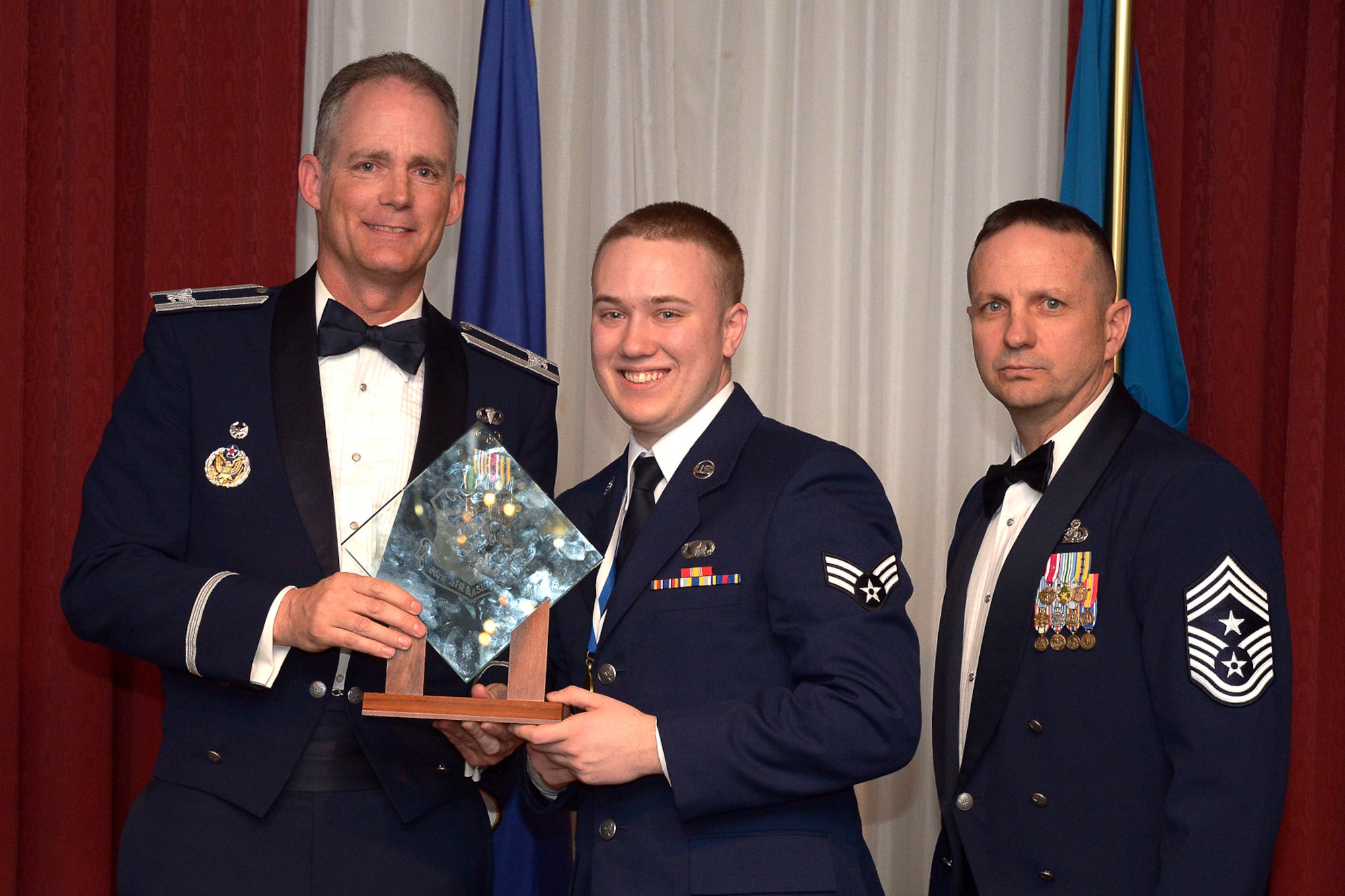 Col. Michael A. Vogel, 66th Air Base Group commander, and Hanscom Command Chief Master Sgt. Craig A. Poling, present Airman 1st Class Mitchell S. Collins, 66th Comptroller Squadron customer service technician, with the Airman of the Year award during the 66 ABG Annual Awards Banquet at the Minuteman Commons, Feb. 6. (U.S. Air Force photo by Jerry Saslav)