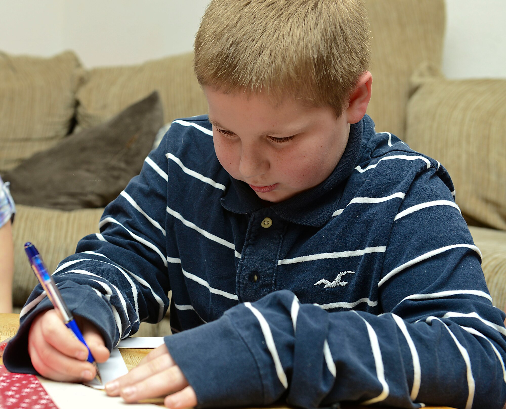 Andrew Hughes, 10-years-old son of U.S. Army Sgt. Justin Hughes, 510th Human Resource Company wheel vehicle mechanic, helps decorate a picture frame at Fort Eustis, Va., Feb. 6, 2015. Hughes is currently deployed and will be missing Valentine’s Day with his family, so the family has created a care package to send him. (U.S. Air Force photo by Senior Airman Kimberly Nagle/Released)