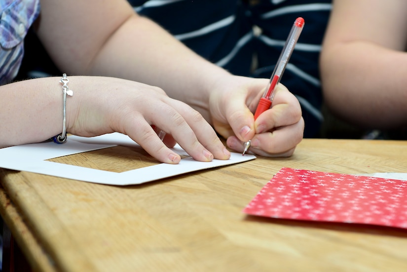 Abigail Becker, 14 year old daughter of U.S. Army Sgt. Justin Hughes, 510th Human Resource Company wheel vehicle mechanic, signs a picture frame at Fort Eustis, Va., Feb. 6, 2015. The frame is part of a Valentine’s Day package sent to Hughes, who is currently deployed. (U.S. Air Force photo by Senior Airman Kimberly Nagle)