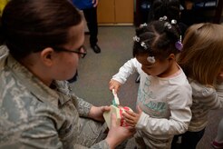 Staff Sgt. Stephanie Rowe, 628th Aerospace Medicine Squadron oral preventative specialist holds onto a set of teeth while Taylor Wallace practices her teeth brushing skills, Feb. 10, 2015 at the General Thomas R. Mikolajcik Child Development Center on Joint base Charleston, S.C.  In honor of Children’s Dental Month, the 628th Medical Group Dental Clinic educated more than 90 children on the importance of brushing their teeth and eating healthy snacks. Each child was given a dental goodie bag containing a toothbrush, toothpaste and a Mr. Tooth activity book. Wallace is the daughter of Staff Sgt. Kirt Wallace, 628th Civil Engineer Squadron. (U.S. Air Force photo / Trisha Gallaway)