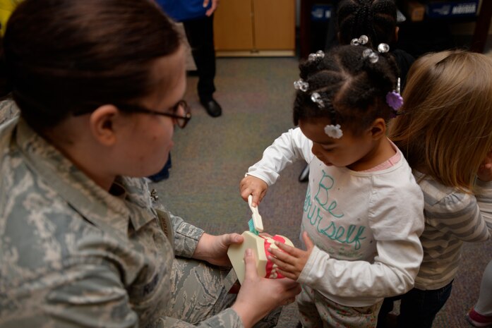Staff Sgt. Stephanie Rowe, 628th Aerospace Medicine Squadron oral preventative specialist holds onto a set of teeth while Taylor Wallace practices her teeth brushing skills, Feb. 10, 2015 at the General Thomas R. Mikolajcik Child Development Center on Joint base Charleston, S.C.  In honor of Children’s Dental Month, the 628th Medical Group Dental Clinic educated more than 90 children on the importance of brushing their teeth and eating healthy snacks. Each child was given a dental goodie bag containing a toothbrush, toothpaste and a Mr. Tooth activity book. Wallace is the daughter of Staff Sgt. Kirt Wallace, 628th Civil Engineer Squadron. (U.S. Air Force photo / Trisha Gallaway)