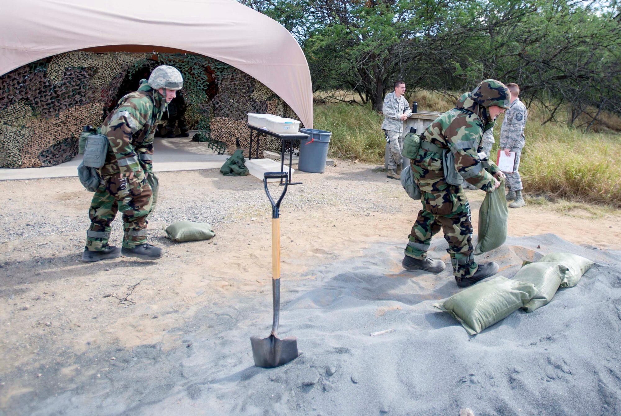 Senior Airman Tavarus Thomas, 647th Security Forces Squadron patrolman, left, and Senior Airman Justin Rager, a 647th SFS entry controller, right, perform buddy care on an injured Airman after a simulated attack during a chemical, biological, radiation, nuclear and explosive exercise at Base X on Joint Base Pearl Harbor-Hickam, Hawaii, Feb. 6, 2015. The exercise tested the group’s ability to survive and operate in a hostile or chemical environment. (U.S. Air Force photo by Tech. Sgt. Terri Paden/RELEASED)