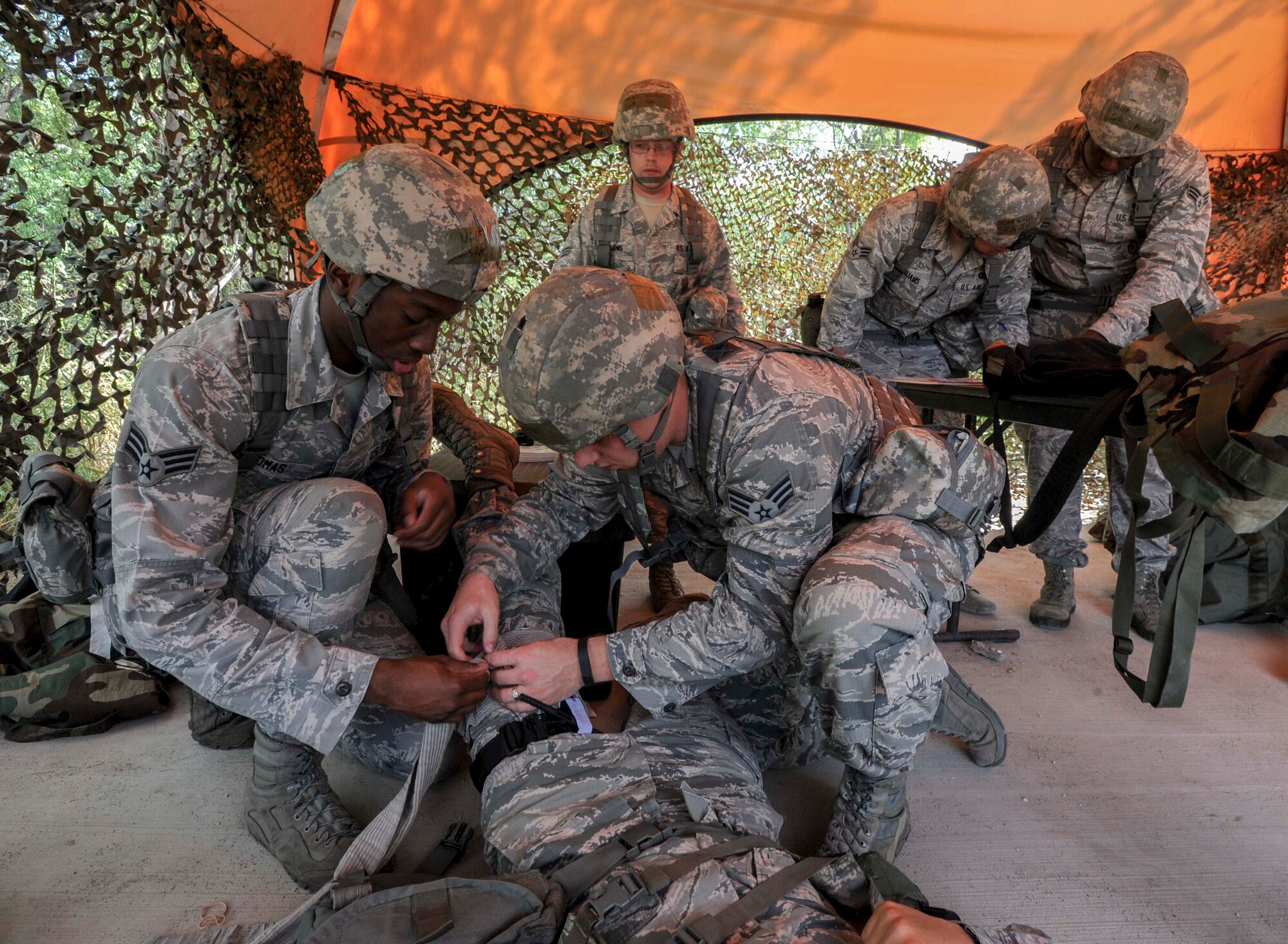 Senior Airman Tavarus Thomas, 647th Security Forces Squadron patrolman, left, and Senior Airman Justin Rager, a 647th SFS entry controller, right, perform buddy care on an injured Airman after a simulated attack during a chemical, biological, radiation, nuclear and explosive exercise at Base X on Joint Base Pearl Harbor-Hickam, Hawaii, Feb. 6, 2015. The exercise tested the group’s ability to survive and operate in a hostile or chemical environment. (U.S. Air Force photo by Tech. Sgt. Terri Paden/RELEASED)