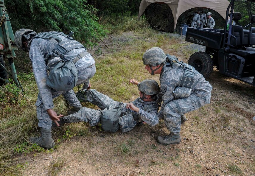 Senior Airman Tavarus Thomas, 647th Security Forces Squadron patrolman, left, and Senior Airman Justin Rager, a 647th SFS entry controller, right, simulate carrying an injured buddy during a chemical, biological, radiation, nuclear and explosive exercise at Base X on Joint Base Pearl Harbor-Hickam, Hawaii, Feb. 6, 2015. The exercise tested the group’s ability to survive and operate in a hostile or chemical environment. (U.S. Air Force photo by Tech. Sgt. Terri Paden/RELEASED)
