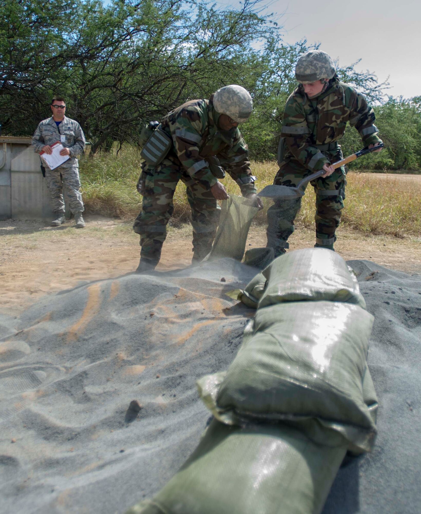 Staff Sgt. Michael Gadlin, 15th Judge Advocate office paralegal, left, and Senior Airman Joseph Smith, 15th Comptroller Squadron financial services technician, fill sandbags during a chemical, biological, radiation, nuclear and explosive exercise at Base X on Joint Base Pearl Harbor-Hickam, Hawaii, Feb. 6, 2015. The exercise tested the group’s ability to survive and operate in a hostile or chemical environment. (U.S. Air Force photo by Tech. Sgt. Terri Paden/RELEASED)