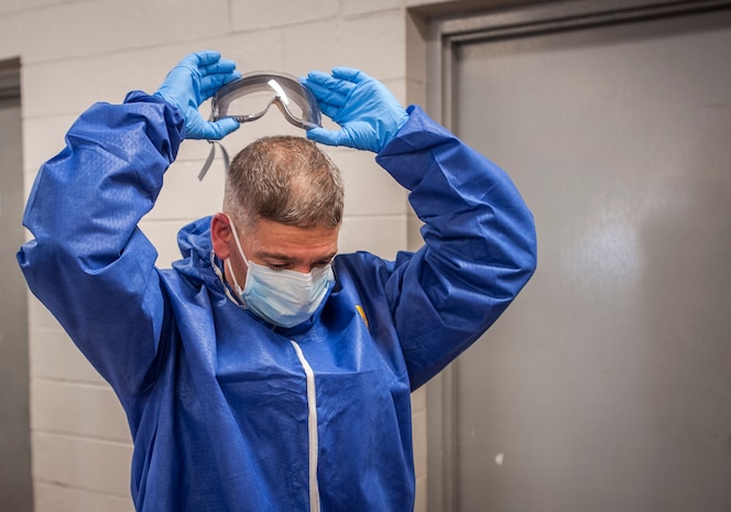 Chief Master Sgt. Shawn Hughes, 437th Airlift Wing command chief, removes protective goggles following an  infection prevention and control practice Feb. 5, 2015, at Joint Base Charleston – Air Base, S.C. The 437th AW leadership stopped by the 437th Aerial Port Squadron to learn more about personal protective equipment and its benefits during the event of an emergency.  (U.S. Air Force photo / Senior Airman Tom Brading)