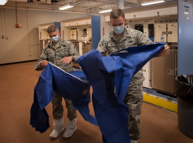 Chief Master Sgt. Shawn Hughes, 437th Airlift Wing command chief, and Col. John Lamontagne, 437th Airlift Wing commander,  put on personal protective equipment during infection prevention and control practice Feb. 5, 2015, at Joint Base Charleston – Air Base, S.C. The 437th AW leadership stopped by the 437th Aerial Port Squadron to learn more about PPE and its benefits during the event of an emergency.  (U.S. Air Force photo / Senior Airman Tom Brading)