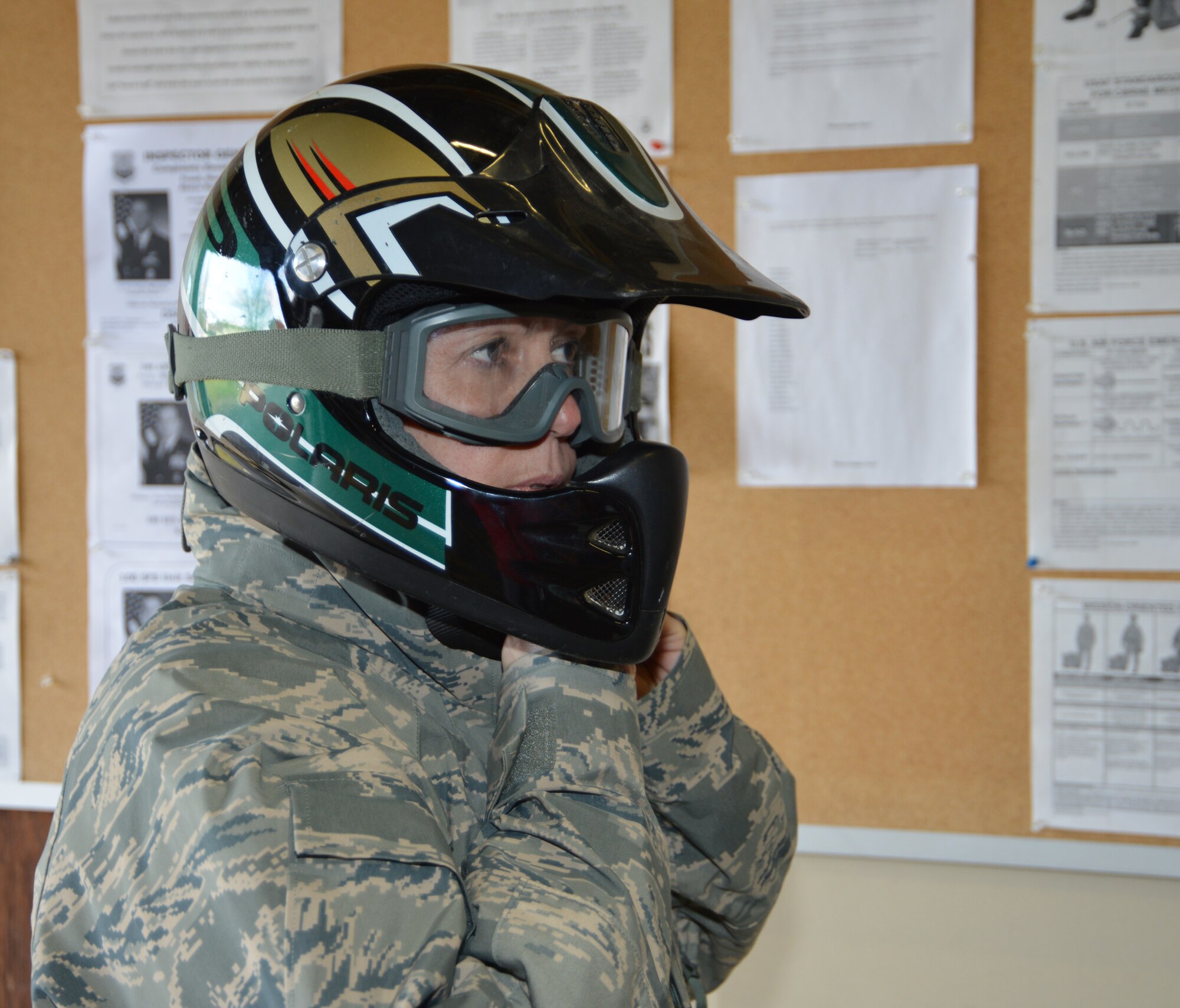 U.S. Air Force Chief Master Sgt. Kathryn Aleshire, 100th Mission Support Group command chief, puts on a helmet as part of the necessary protective gear before receiving safety training to operate an all-terrain vehicle with 100th Security Forces Squadron Defenders Feb. 9, 2015, on RAF Mildenhall, England. Aleshire, along with U.S. Air Force Col. David Avila, 100th MSG commander, rode ATVs as they performed perimeter checks around the base. Regular perimeter checks are essential to ensure the structural integrity of the fence. (U.S. Air Force photo by Karen Abeyasekere/Released)