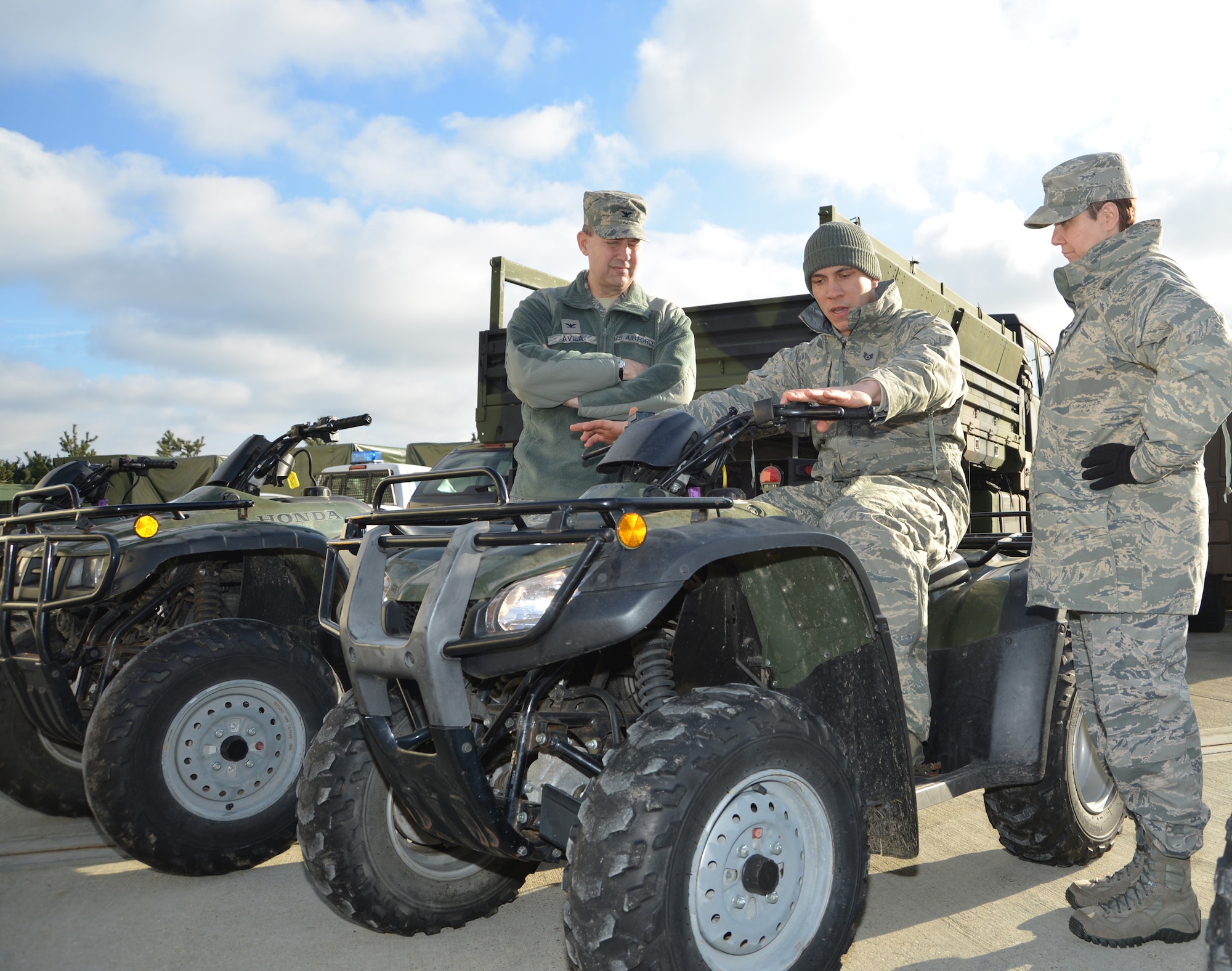 U.S. Air Force Staff Sergeant Samuel Perez, center, 100th Security Forces Squadron supply NCO in charge from Plainfield, Conn., explains how to control an all-terrain vehicle to U.S. Air Force Col. David Avila, left, 100th Mission Support Group commander, and U.S. Air Force Chief Master Sgt. Kathryn Aleshire, 100th MSG command chief, during their visit to the 100th SFS Feb. 9, 2015, on RAF Mildenhall, England. Two 100th SFS Defenders rode around with the 100th MSG leadership, performing perimeter checks around the base and highlighting the importance of ATVs. (U.S. Air Force photo by Karen Abeyasekere/Released)
