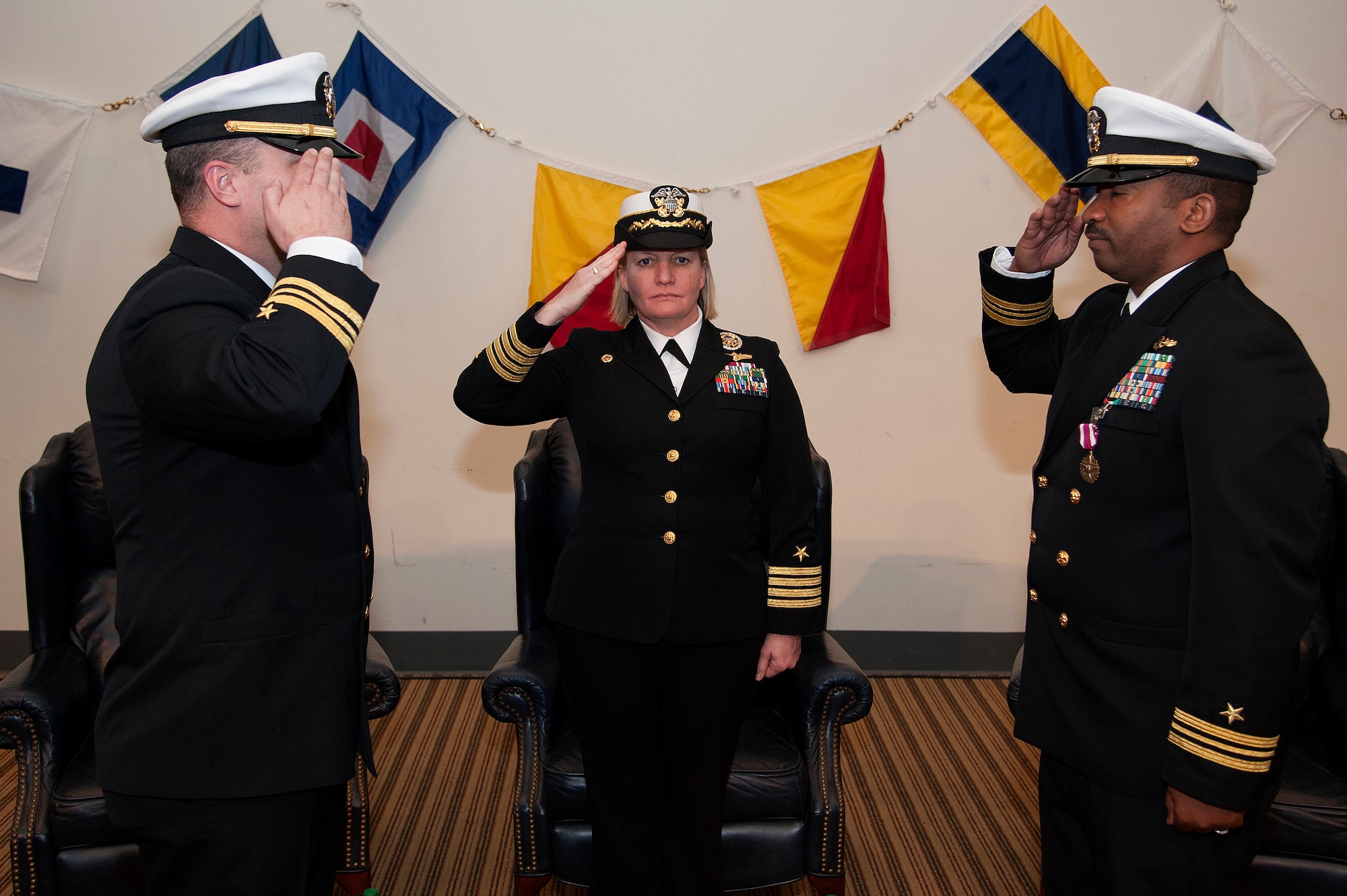 GOODFELLOW AIR FORCE BASE, Texas – U.S. Navy Lt. Cmdr. Cornell A. Woods, right, relinquishes command of the Navy Center for Information Dominance Detachment to Lt. Cmdr. Chris M. Allen, left, during the change of charge ceremony officiated by Capt. Maureen Fox, Center for Information Dominance Commander, at the Event Center Feb. 6. (U.S. Air Force photo/ Airman 1st Class Devin Boyer)