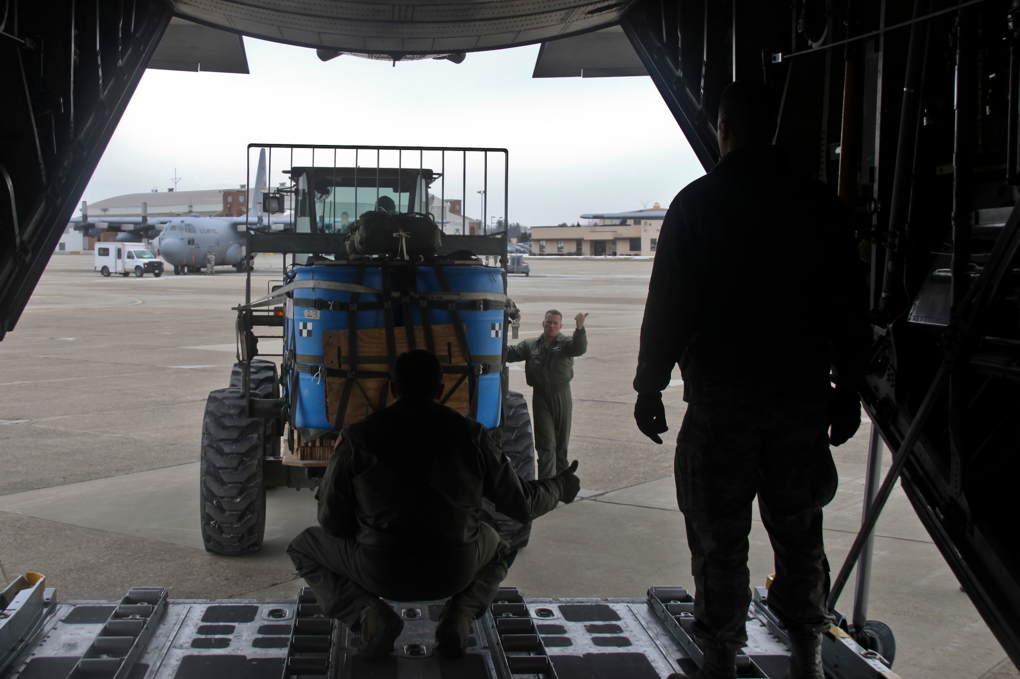 Master Sgt. John Cellurale and Senior Master Sgt. Dave Robbins, loadmasters with the 911th Operations Group, communicate with hand signals to guide a load of cargo into the rear of a C-130 Hercules aircraft at Pittsburgh International Airport Air Reserve Station, February 8, 2015. The loadmasters work with air transportation specialists from the 32nd Aerial Port Squadron to load containerized delivery systems to be used in an air drop. (U.S. Air Force photo by Staff Sgt. Jonathan Hehnly)