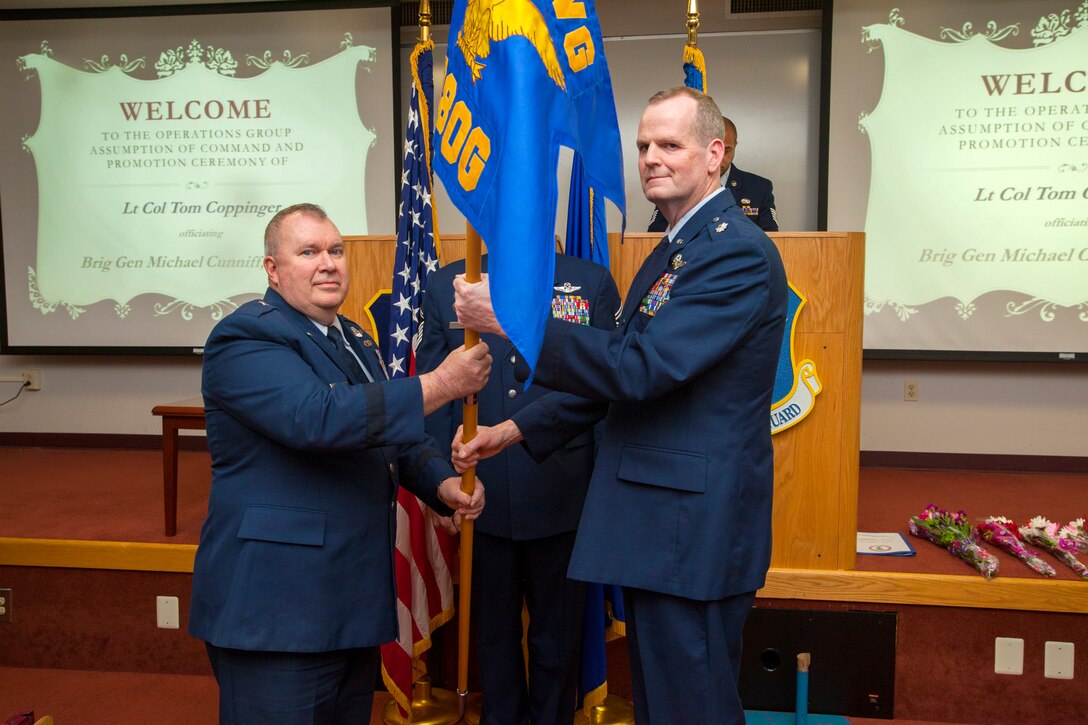 Brig. Gen. Michael L. Cunniff, left, The Adjutant General of New Jersey, passes Lt. Col. Thomas P. Coppinger the Operations Group guidon during an Assumption of Command ceremony at Joint Base McGuire-Dix-Lakehurst, N.J., Feb. 8, 2015. Coppinger was also promoted to colonel during the ceremony. The 108th Operations Group is part of the 108th Wing, New Jersey Air National Guard. (U.S. Air National Guard photo by Master Sgt. Mark C. Olsen/Released)