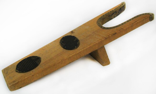 A boot jack is a tool used in the removal of boots. The boot heel is placed in the U-shaped opening of the boot jack, while the other foot is standing on the flat end of the boot jack, and then with a pull the foot is freed from the boot. Boot jacks help prevent stooping and struggling when removing tall riding boots that have been worn all day. And for sanitary purposes, they can keep hands clean of mud and manure while dirty riding boots are being removed. (U.S. Air Force photo)