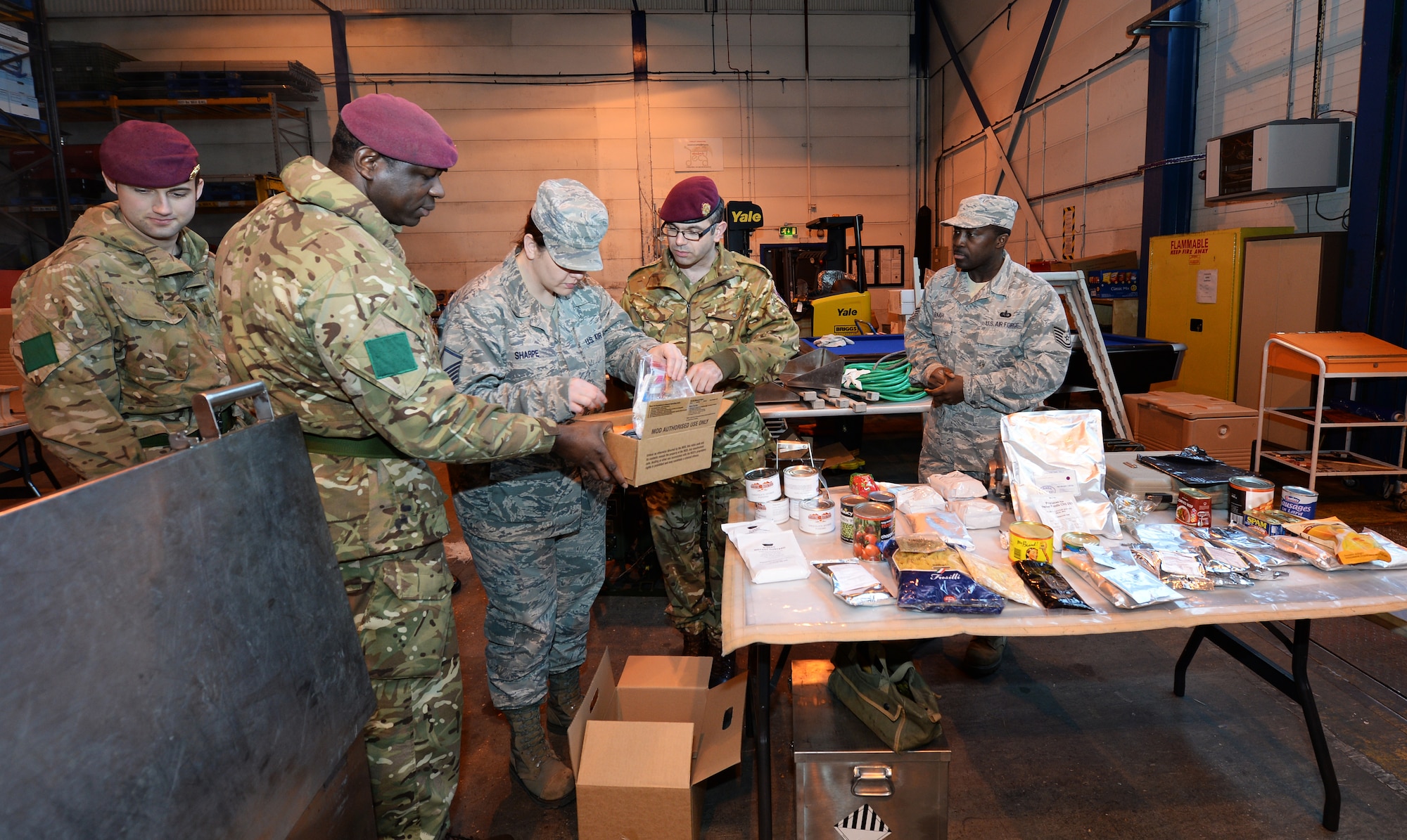 Master Sgt. Lindsey Sharpe, 48th Force Support Squadron NCO in charge of readiness, compares Meals Ready to Eat with Royal Army cooks from 3rd Battalion, Parachute Regiment, Colchester garrison, during their visit at Royal Air Force Lakenheath, England, Jan. 4, 2015. RA cooks visited to gain knowledge and experience on how American forces cater dining facilities. (U.S. Air Force photo by Staff Sgt. Emerson Nuñez/Released)