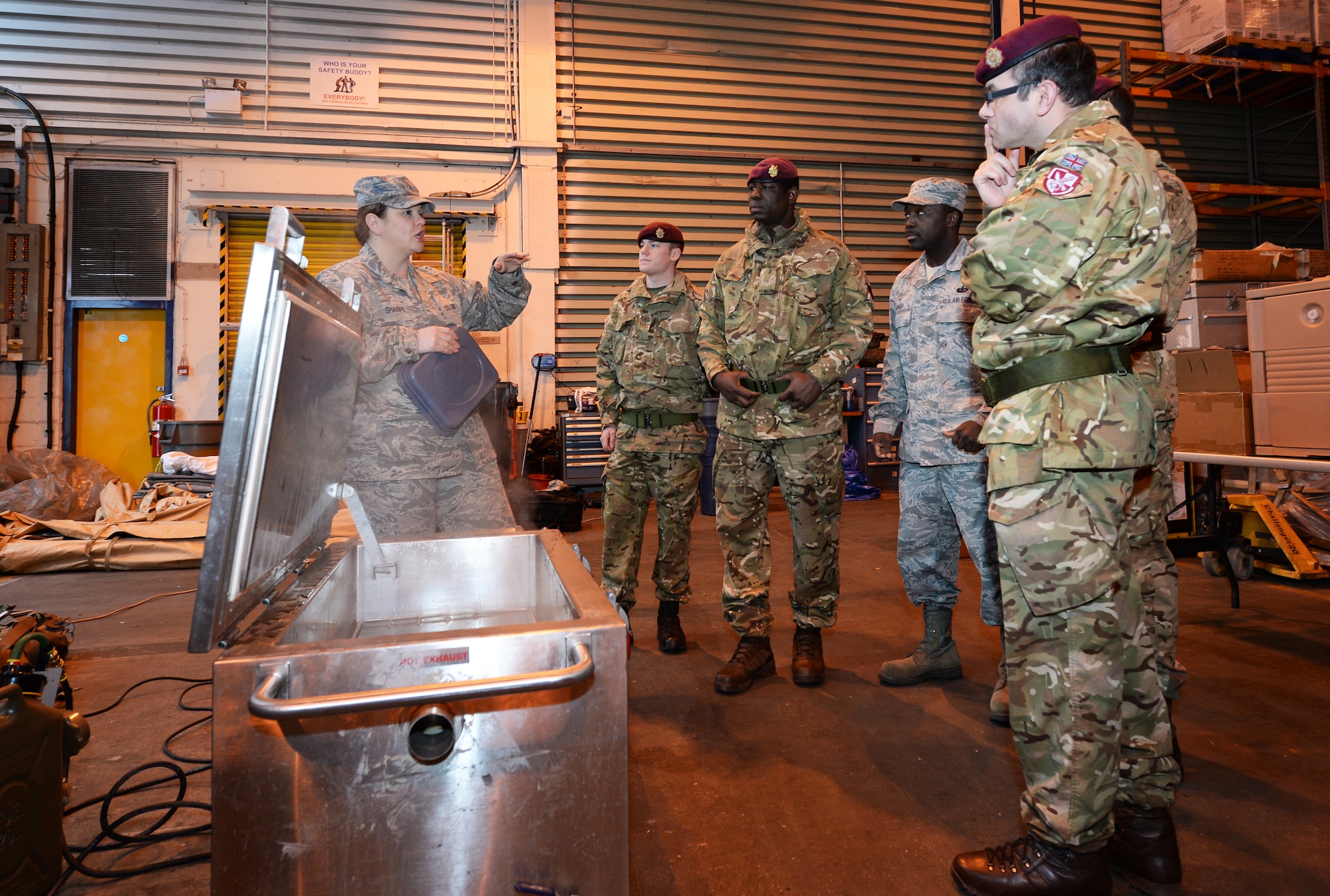 Master Sgt. Lindsey Sharpe, 48th Force Support Squadron NCO in charge of readiness, showcases the Single Palletized Expeditionary Kitchen to Royal Army cooks from 3rd Battalion, Parachute Regiment, Colchester garrison, during their visit at Royal Air Force Lakenheath, England, Jan. 4, 2015. 48th FSS food service members demonstrated normal operations in both the dining facility and the SPEK, which is normally used to provide hot meals down range. (U.S. Air Force photo by Staff Sgt. Emerson Nuñez/Released)