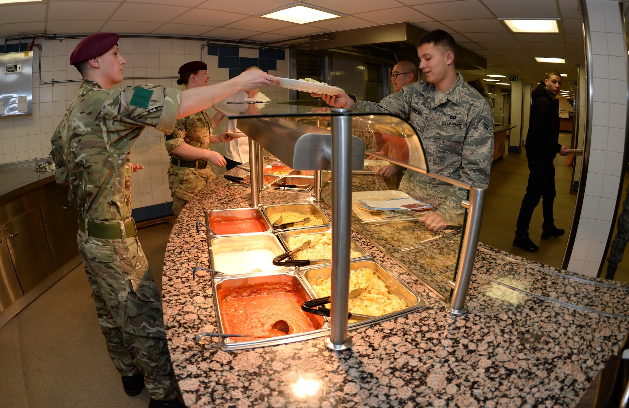 Royal Army cooks from 3rd Battalion, Parachute Regiment, Colchester garrison, serve 48th Fighter Wing Airmen during their visit to the Knight's Table Dining Facility at Royal Air Force Lakenheath, England, Jan. 3, 2015. RA cooks and 48th Force Support Squadron food service members showcased and compared cooking procedures during the visit. (U.S. Air Force photo by Staff Sgt. Emerson Nuñez/Released)