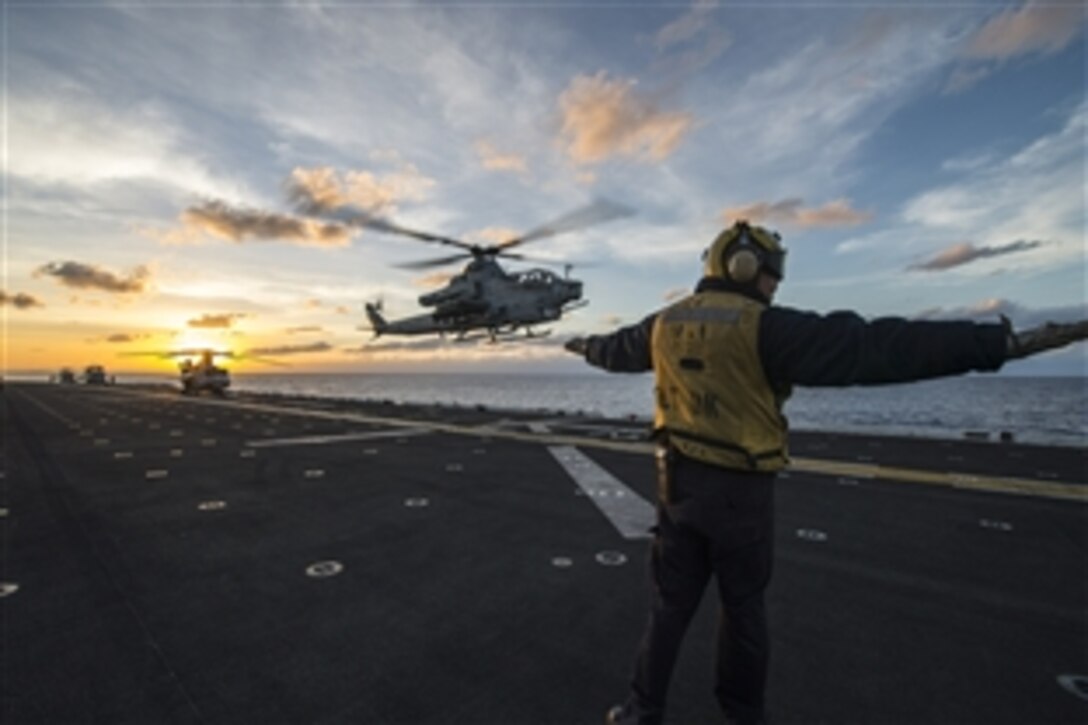 A U.S. Navy sailor signals an AH-1Z Viper helicopter to land on the amphibious assault ship USS Makin Island during routine flight operations in the Pacific Ocean, Feb. 4, 2015. 
