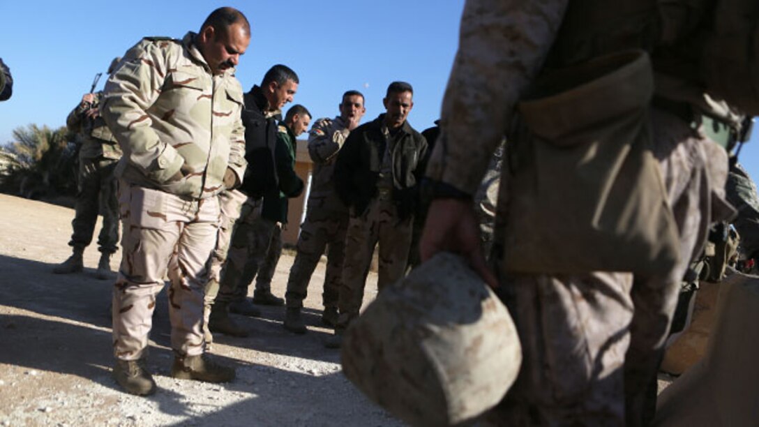 U.S. Marine Chief Warrant Officer 2 Juan Rodriguez, an explosive ordnance disposal officer with Task Force Al Asad, and brigade-level leaders of the Iraqi Army walk through an improvised explosive device training lane aboard Al Asad Air Base, Iraq, Jan. 31, 2015. The classes showed the leadership the training their soldiers will receive in the future and gave them a look at tactics being used today by Da'esh.