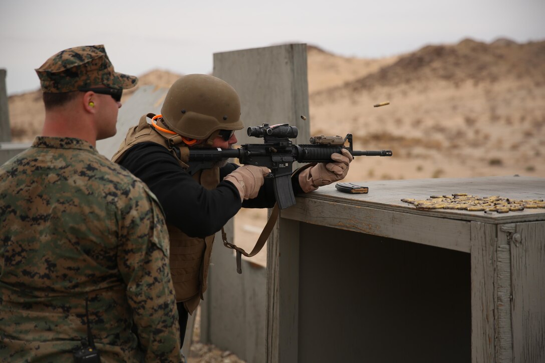 Sgt. Kris Frillman, training cadre, 7th Marine Regiment, a native of Thayer, Mo., assists Mark Greenwood, director of public works, City of Palm Desert, as during the live-fire portion of the city of Palm Desert's tour of the Combat Center, Jan. 28, 2015. Throughout the tour, Marines from the Regiment assisted and answered questions. (Official Marine Corps Photo by Lance Cpl. Julio McGraw)