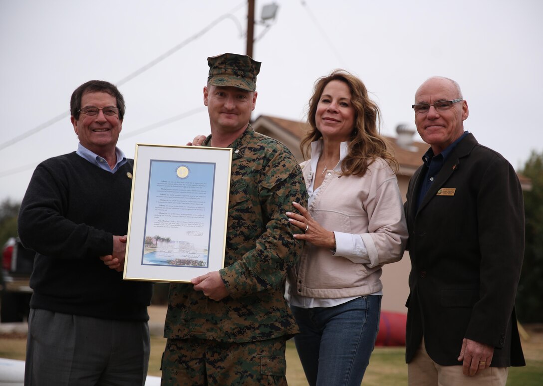 Lt. Col. Jared Spurlock, executive officer, 7th Marine Regiment, accepts a certificate announcing the adoption of 7th Marine Regiment by the city of Palm Desert from Van Tanner, former mayor, City of Palm Desert,  and Palm Desert council members, Jan Harnik and Sabby Jonathan, during the city’s tour of the Combat Center, Jan. 28, 2015. (Official Marine Corps Photo by Lance Cpl. Julio McGraw/Released)