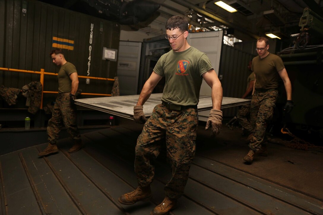 Marines with the 11th Marine Expeditionary Unit move a floor panel, while building a Personnel Transport System aboard the amphibious assault ship USS Makin Island (LHD 8), Feb. 10. The Makin Island Amphibious Ready Group and the embarked 11th MEU are deployed in support of maritime security operations and theater security cooperation efforts in the U.S. 7th Fleet area of responsibility. (U.S. Marine Corps photos by Cpl. Demetrius Morgan/Released)  