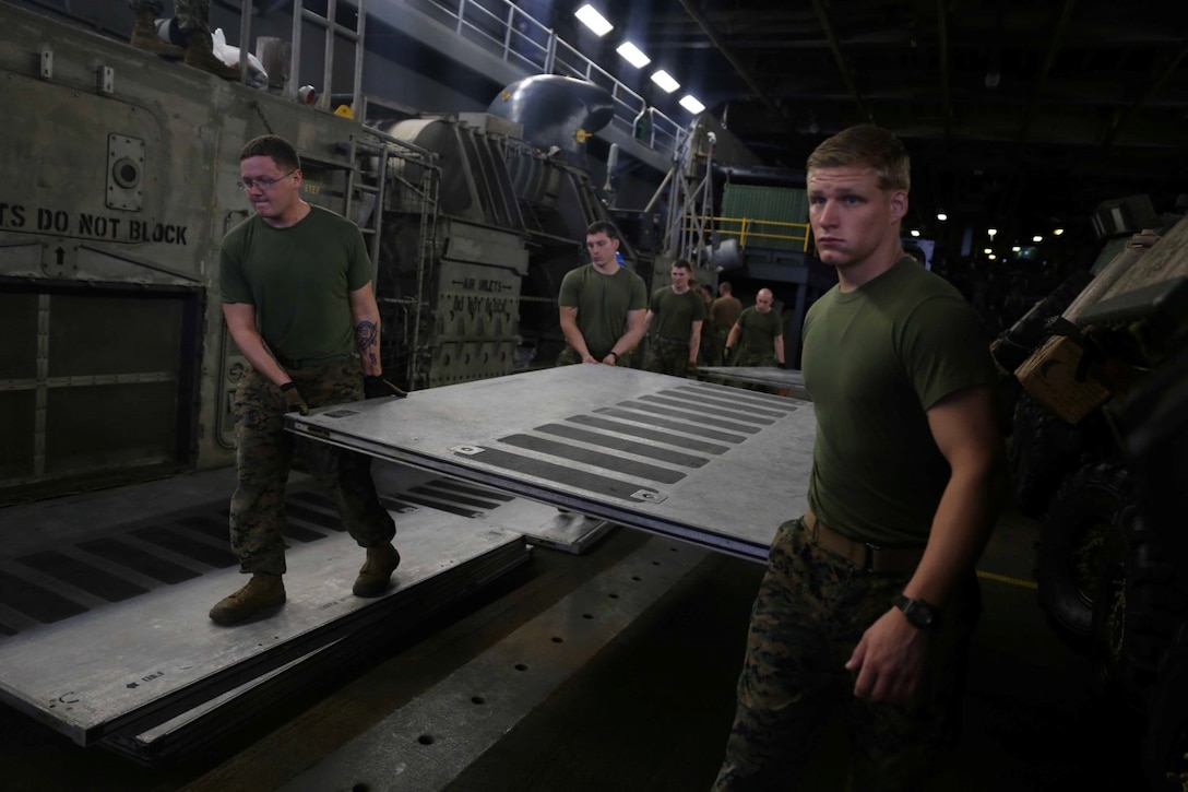 Marines with the 11th Marine Expeditionary Unit move a floor panel, while building a Personnel Transport System aboard the amphibious assault ship USS Makin Island (LHD 8), Feb. 10. The Makin Island Amphibious Ready Group and the embarked 11th MEU are deployed in support of maritime security operations and theater security cooperation efforts in the U.S. 7th Fleet area of responsibility. (U.S. Marine Corps photos by Cpl. Demetrius Morgan/Released)     