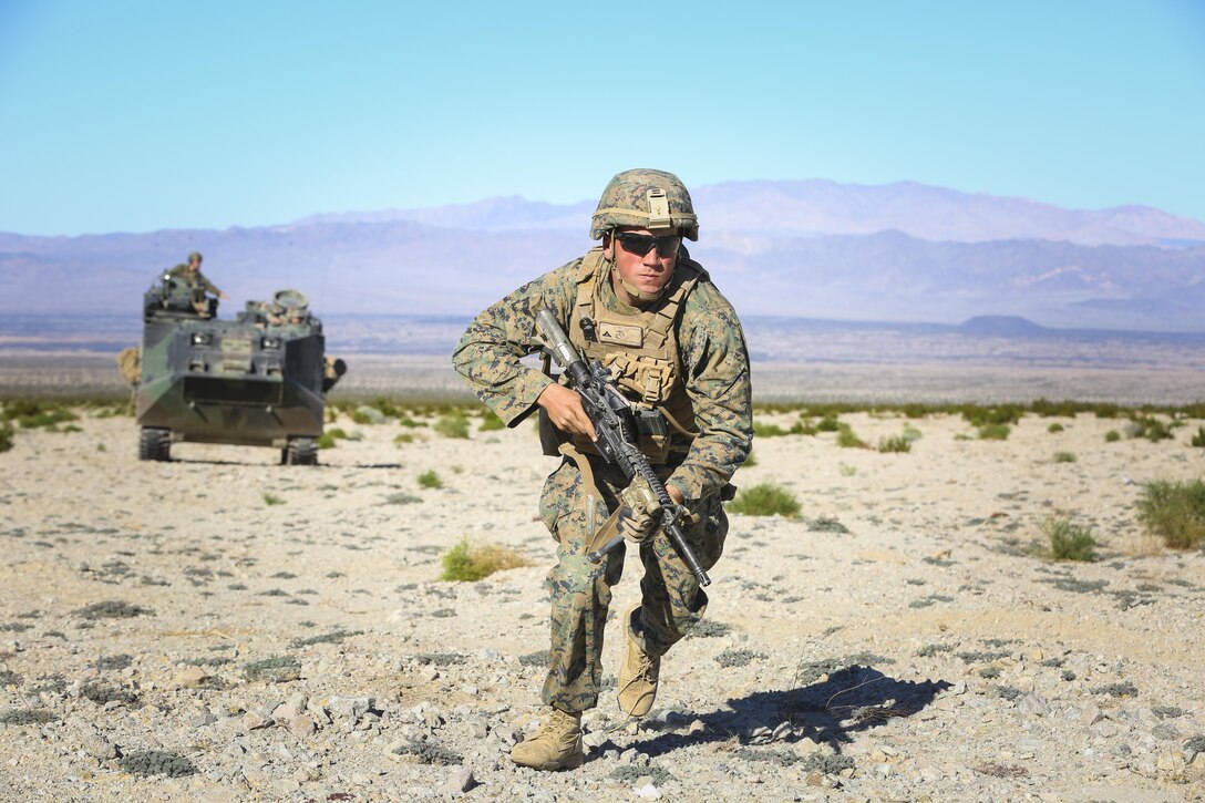 Lance Cpl. Luke Conrad, assaultman, Company I, 3rd Battalion, 7th Marine Regiment, advances toward an objective from an Assault Amphibious Vehicle during an assault on a Military Operation on Urbanized Terrain town on Range 210 during the Marine Corps Combat Readiness Evaluation Exercise aboard the Combat Center, Jan. 19, 2015. Each company in 3/7 ran a dry- fire and live-fire assault evolution through the MOUT town. (Official Marine Corps Photo by Lance Cpl. Julio McGraw/Released)