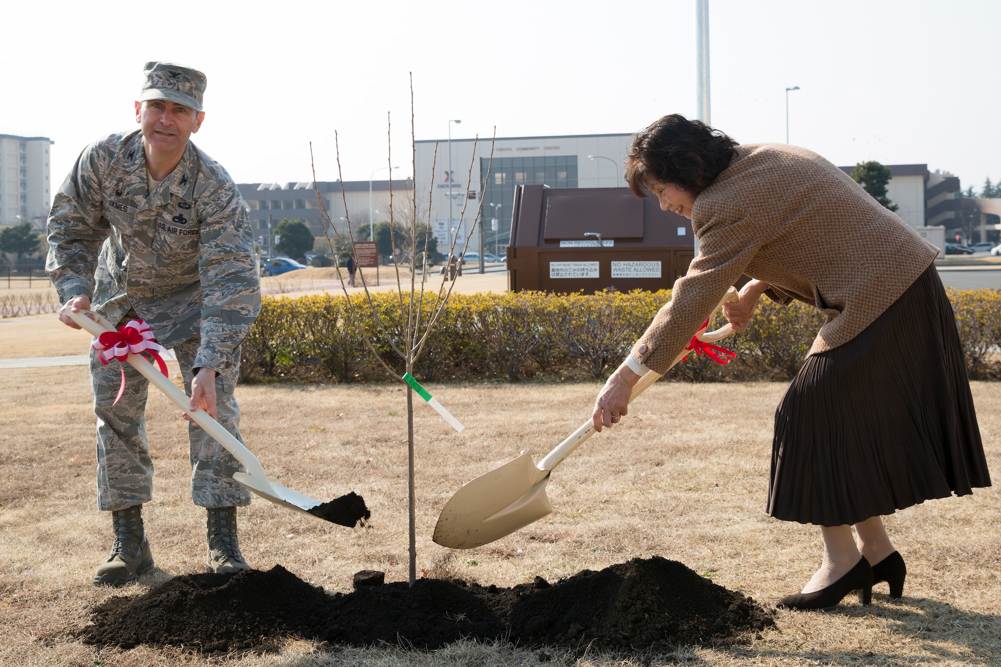 Col. Steven James, 374th Maintenance Group commander, and Yasue Sugiura, Hamura-Yokota Friendship Club president, shovel soil during the cherry tree planting ceremony at Yokota Air Base, Japan, Feb. 12, 2015. Community leaders from Fussa city donated cherry blossom saplings descended from the cherry trees given to the U.S from Japan in 1912. (U.S. Air Force photo by Osakabe Yasuo/Released)