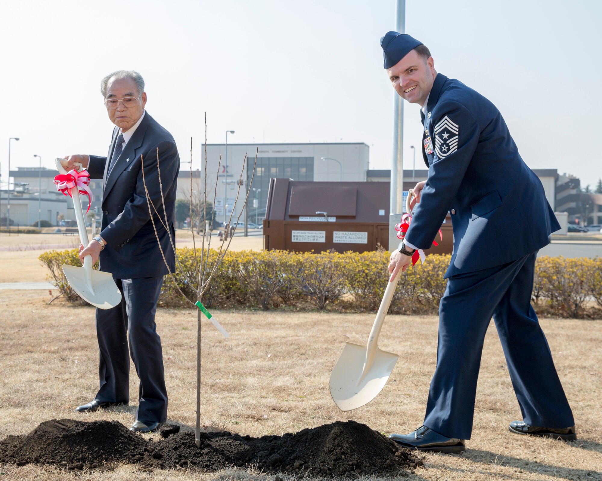 Chief Master Sgt. Paul Elliott, 374th Airlift Wing command chief, and Muneyasu Hoshino, Akishima-Yokota Friendship club vice president, shovel soil during the cherry tree planting ceremony at Yokota Air Base, Japan, Feb. 12, 2015. Community leaders from Fussa city donated cherry blossom saplings descended from the cherry trees given to the U.S from Japan in 1912. (U.S. Air Force photo by Osakabe Yasuo/Released)