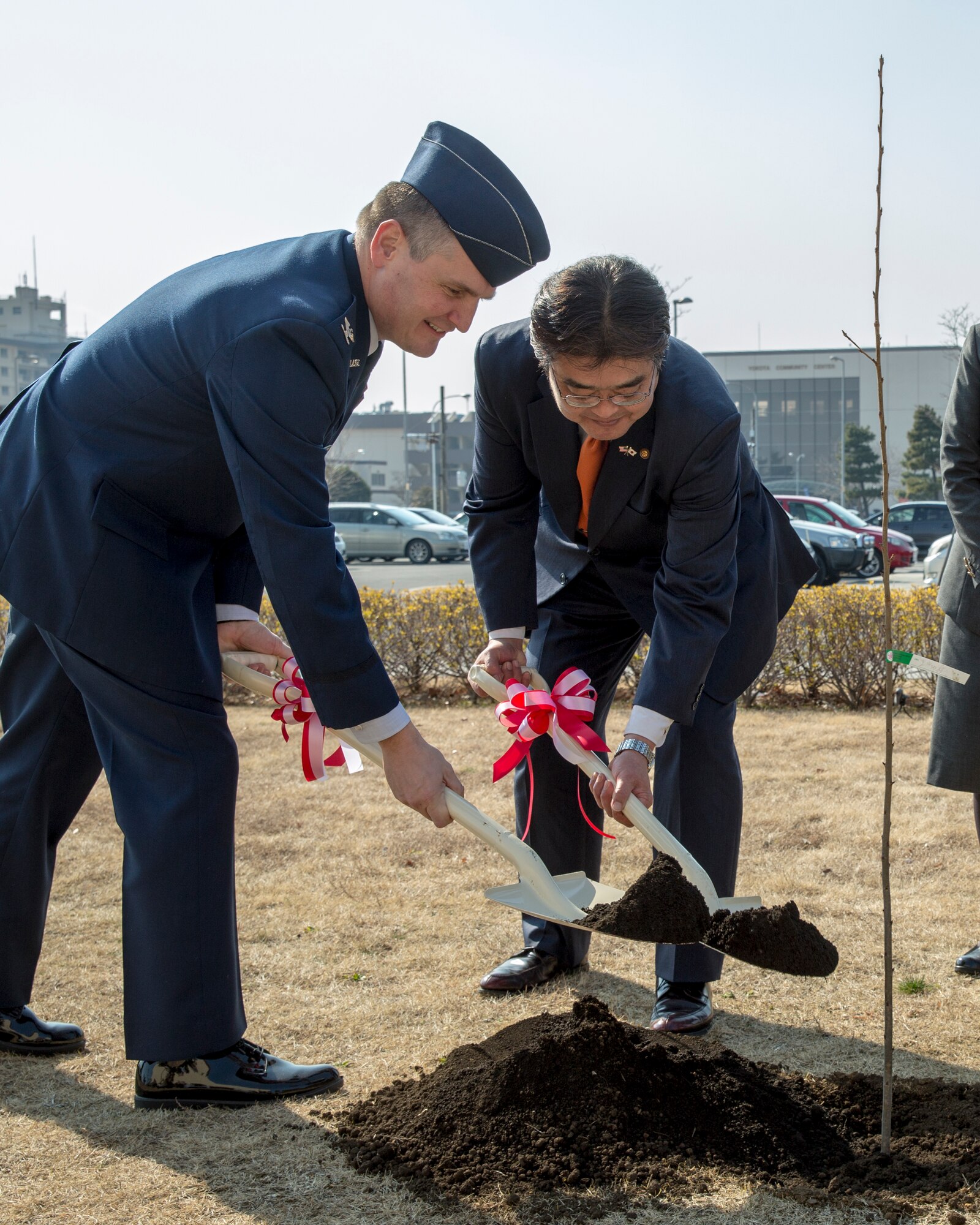 Col. Douglas DeLaMater, 374th Airlift Wing commander, and Ikuo Kato, Fussa city mayor, shovel soil during the cherry tree planting ceremony at Yokota Air Base, Japan, Feb. 12, 2015. Community leaders from Fussa city donated cherry blossom trees descended from the cherry saplings given to the U.S from Japan in 1912. (U.S. Air Force photo by Osakabe Yasuo/Released)