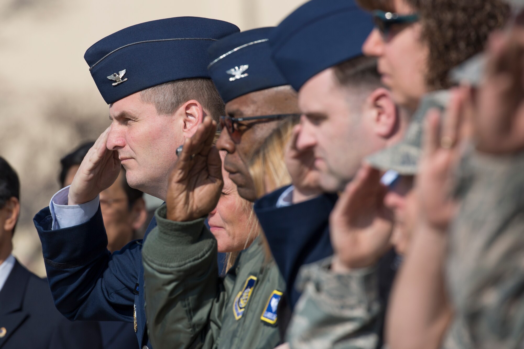 Leaderships from the 374th Airlift Wing salute during the singing of the Japanese and American National Anthem, Feb. 12, 2015, during the cherry tree planting ceremony at Yokota Air Base, Japan. Community leaders from Fussa city donated cherry blossom saplings descended from the cherry trees given to the U.S from Japan in 1912. (U.S. Air Force photo by Osakabe Yasuo/Released)
