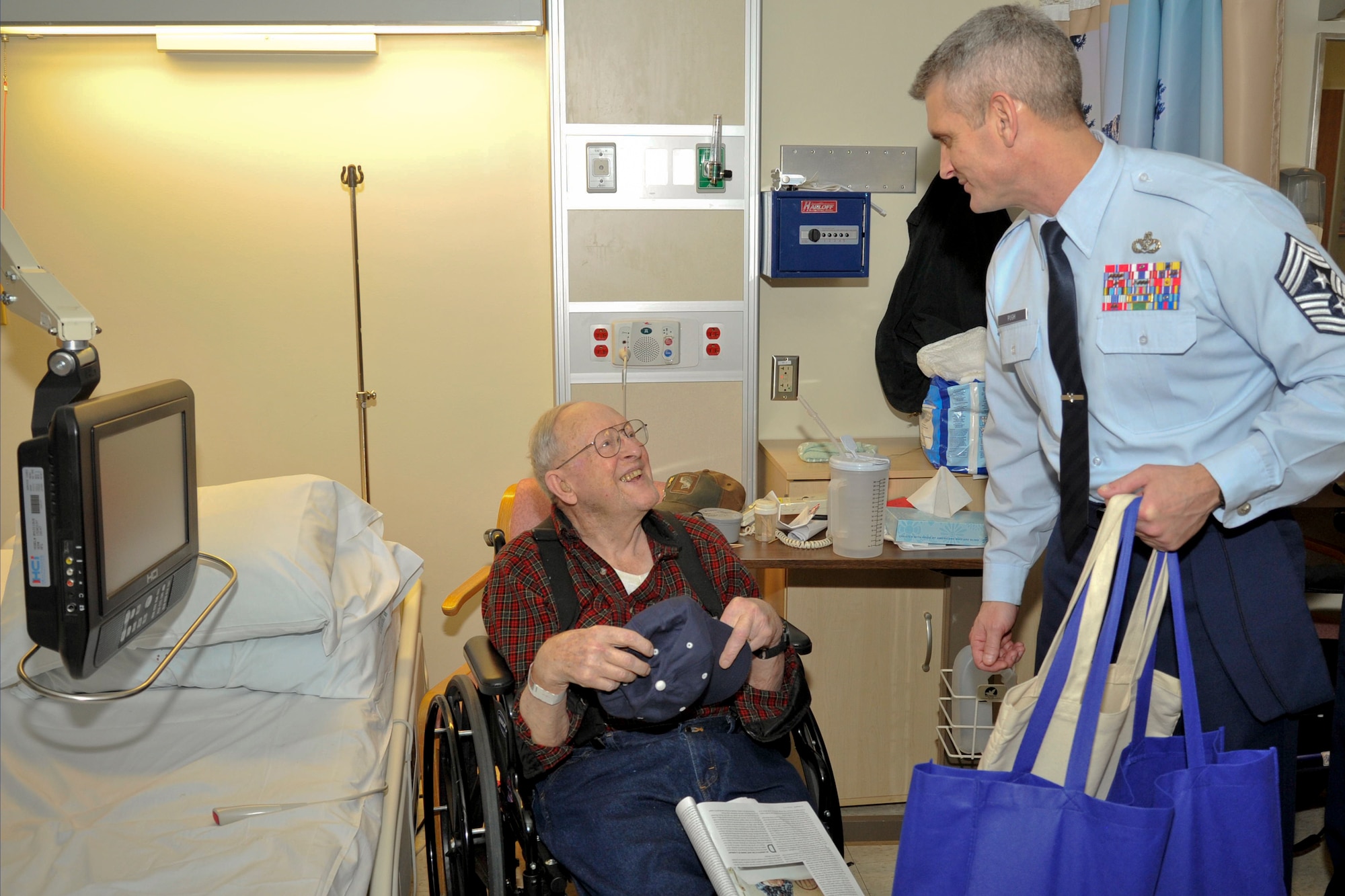 Chief Master Sgt. Christian Pugh, 92nd Air Refueling Wing command chief, presents a National Salute to Veteran Patients hat to a veteran at the Spokane Veteran Medical Center Feb. 11, 2015, in Spokane, Wash. Team Fairchild leaders had the opportunity to pay visits to veterans in special wards of the hospital. (U.S. Air Force photo/Airman 1st Class Nicolo J. Daniello)
