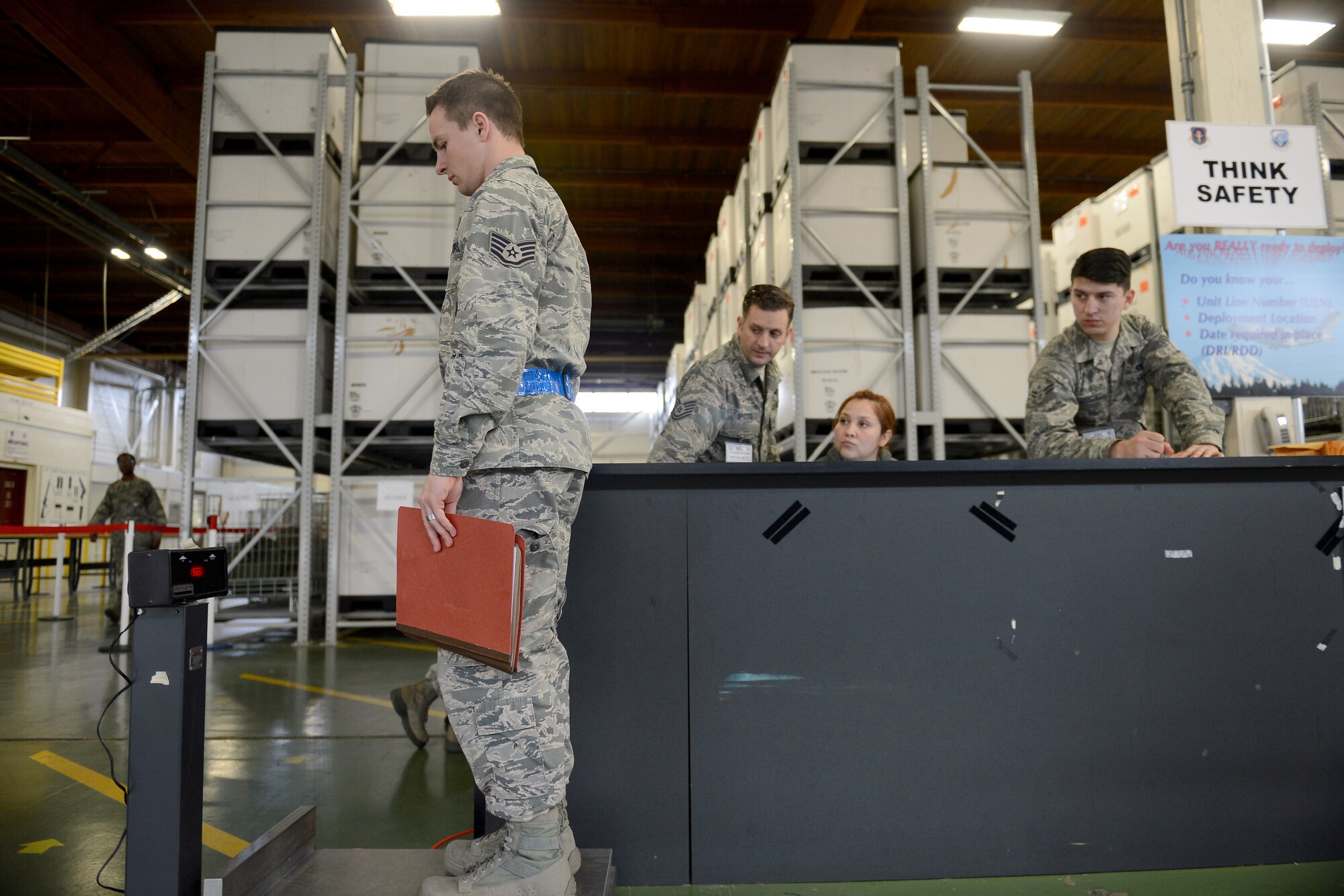 Staff Sgt. Tyler Moore, 627th Security Forces Squadron instructor, steps on a scale to calculate his weight as Airmen from separate organizations watch Feb. 3, 2015, during Exercise SNAPSHOT at Joint Base Lewis-McChord, Wash. The purpose of the exercise was to test deployment readiness and ability to execute direct delivery combat operation of McChord Airmen. (U.S. Air Force photo/Airman 1st Class Keoni Chavarria)