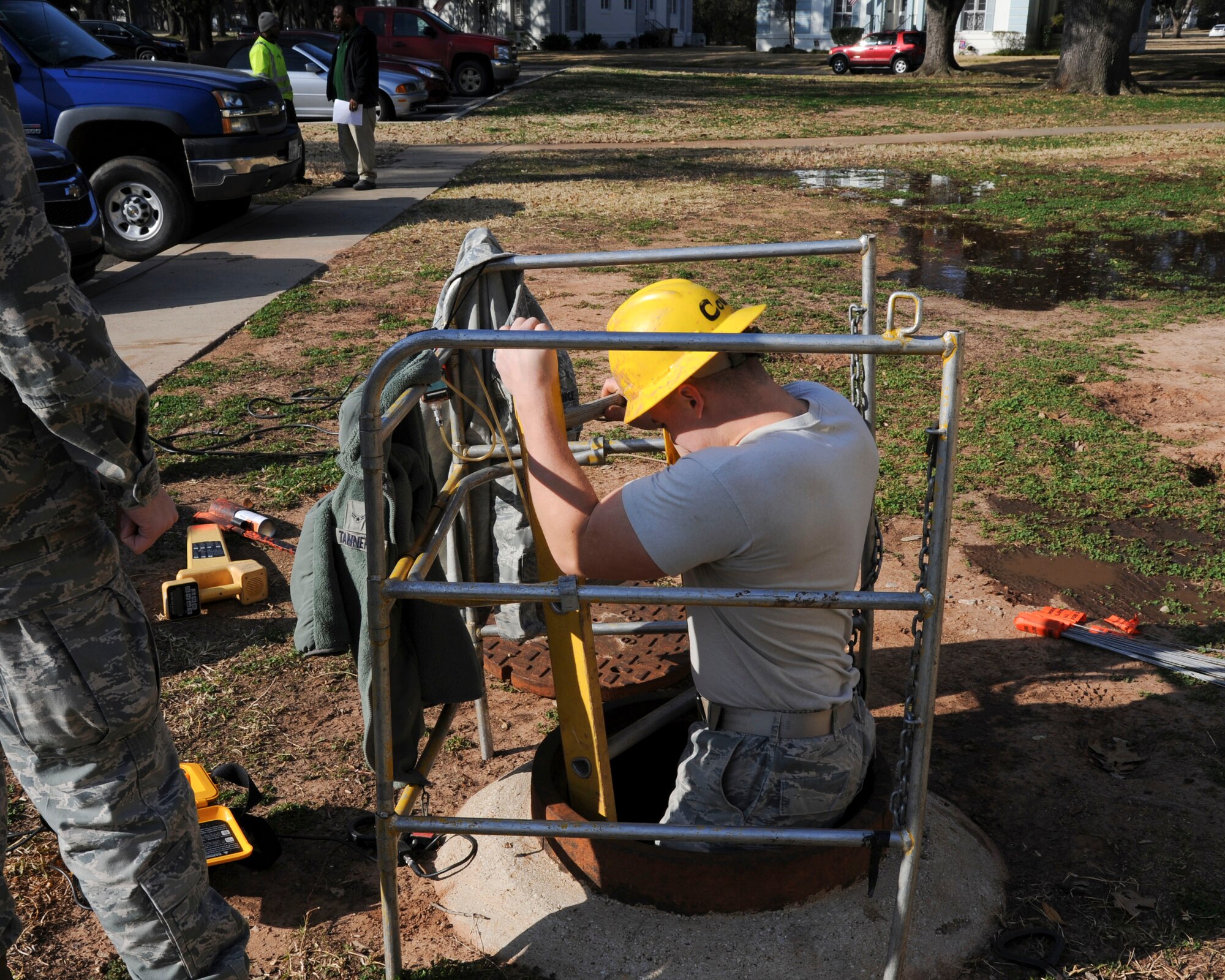 Senior Airman Creston Jenkins, 2nd Communications Squadron cable and antenna systems, descends into a manhole on Barksdale Air Force Base, La., Feb. 11, 2015. To prevent loss of communication, Cable Dawgs Airmen locate and mark buried cables with a cable locater prior to construction or digging projects. (U.S. Air Force photo/ Senior Airman Jannelle Dickey)