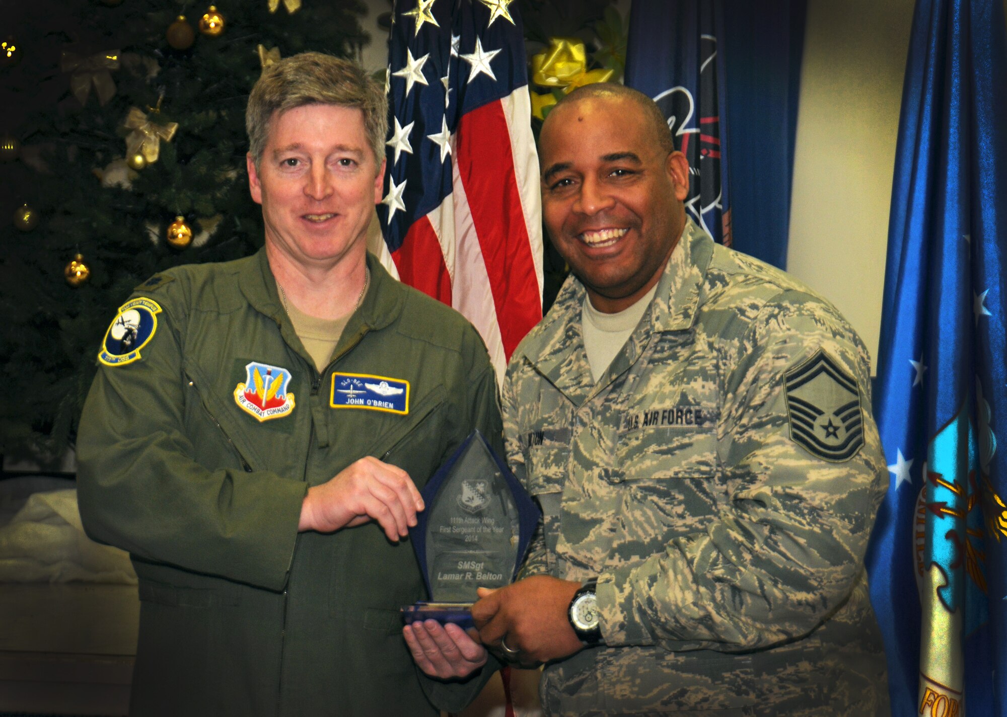 Lt. Col John O'Brien, 111th Operation Support Squadron commander, hands an award to Senior Master Sgt. Lamar Belton, 111th OSS first sergeant,  as the 111th Attack Wing recognized five 2014 Annual Award recipients during a ceremony held here Feb. 8, 2015 at the headquarters building, Horsham Air Guard Station, Pa. The categories in which the Guardsmen competed were Airman, Noncommissioned Officer, First Sergeant, Senior NCO and Company Grade Officer of the Year. The winners each received and plaque and certificate to recognize their achievements.(U.S. Air National Guard photo by Staff Sgt. Michael Stauffer/Released)