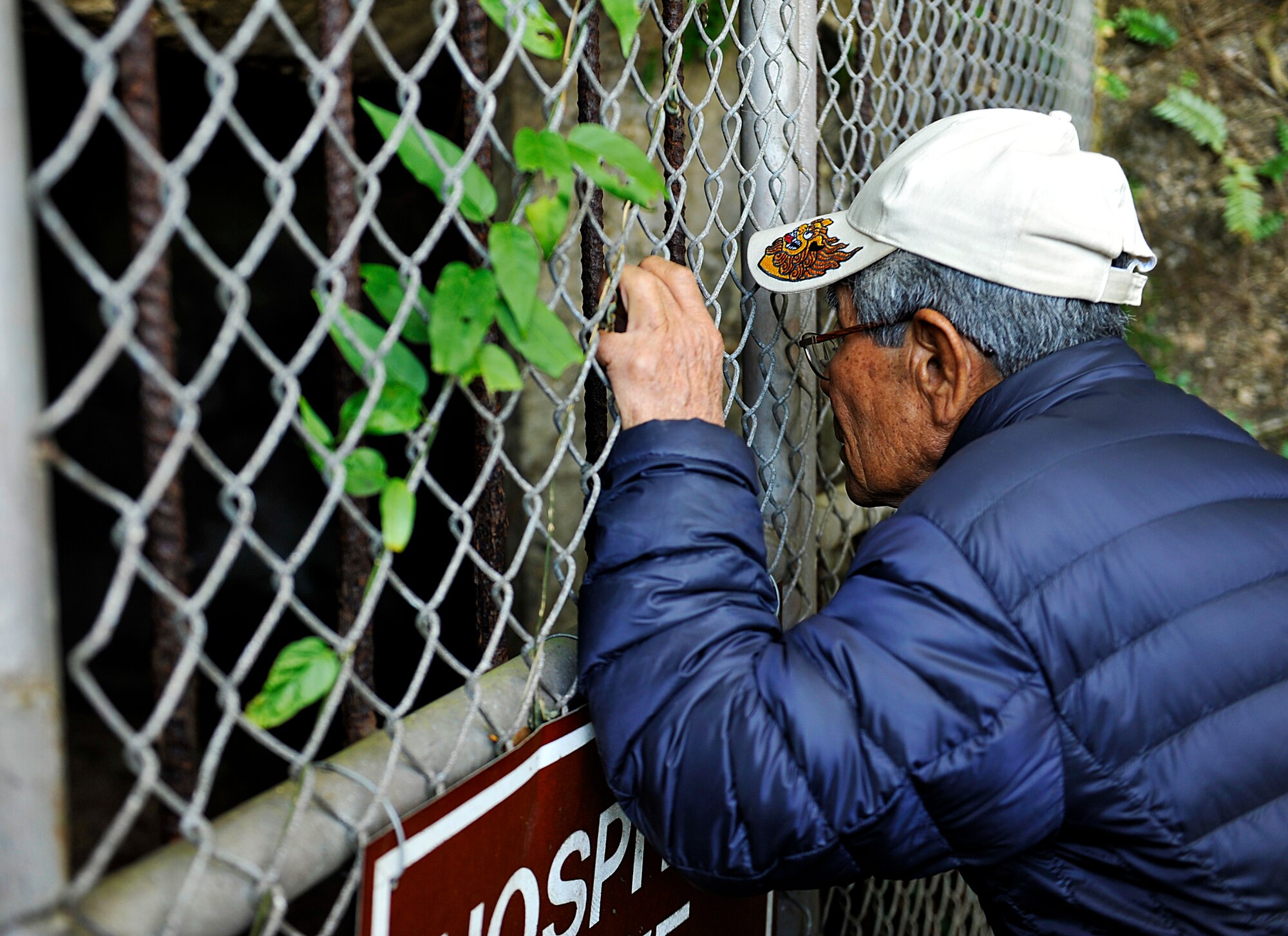 A man from Chatan Hometown Association peeks through the bunker during a sacred site visit on Kadena Air Base, Okinawa, Japan, Feb. 11, 2015. The bunker was used as shelter for local people during the World War II. (U.S. Air Force photo by Naoto Anazawa)


