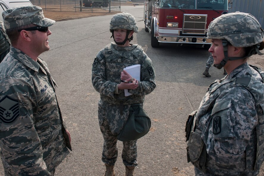 Master Sgt. Jeremy Phillips, 8th Civil Engineer Squadron Explosive Ordnance Disposal team leader (left), Chief Warrant Officer 2 Jessica Willis, Alpha Battery, 2nd Battalion, 1st Air Defense Artillery air and missile defense tactician (center), and Capt. Jessica Bohache, A/2-1 ADA BN battery commander, discuss EOD’s response to a simulated dropped patriot missile canister during the battalion’s quarterly field training exercise at Kunsan Air Base, Republic of Korea, Feb. 11, 2015. Incorporating the Air Force’s response into the missile inject presented a new training opportunity for not only soldiers directly involved, but also for the Wolf Pack. (U.S. Air Force photo by Senior Airman Katrina Heikkinen/Released)