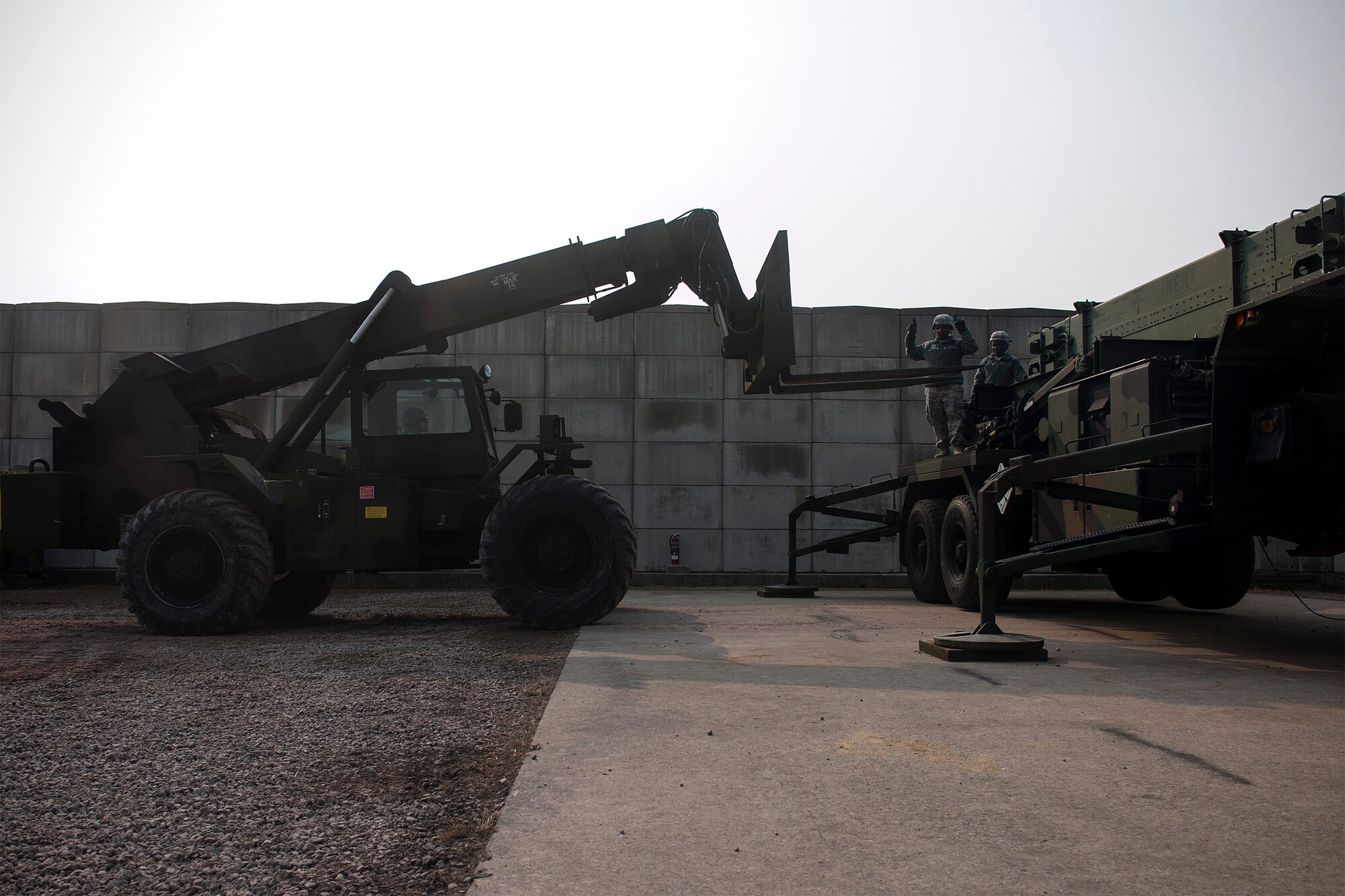Alpha Battery, 2nd Battalion, 1st Air Defense Artillery maintainers operate and direct a forklift during a quarterly field training exercise at Kunsan Air Base, Republic of Korea, Feb. 11, 2015. Soldiers and Airmen from the 8th Security Force Squadron, 8th Civil Engineer Squadron Explosive Ordnance Disposal Flight and 8 CES Fire Department responded to a simulated dropped patriot missile canister. (U.S. Air Force photo by Senior Airman Katrina Heikkinen/Released)